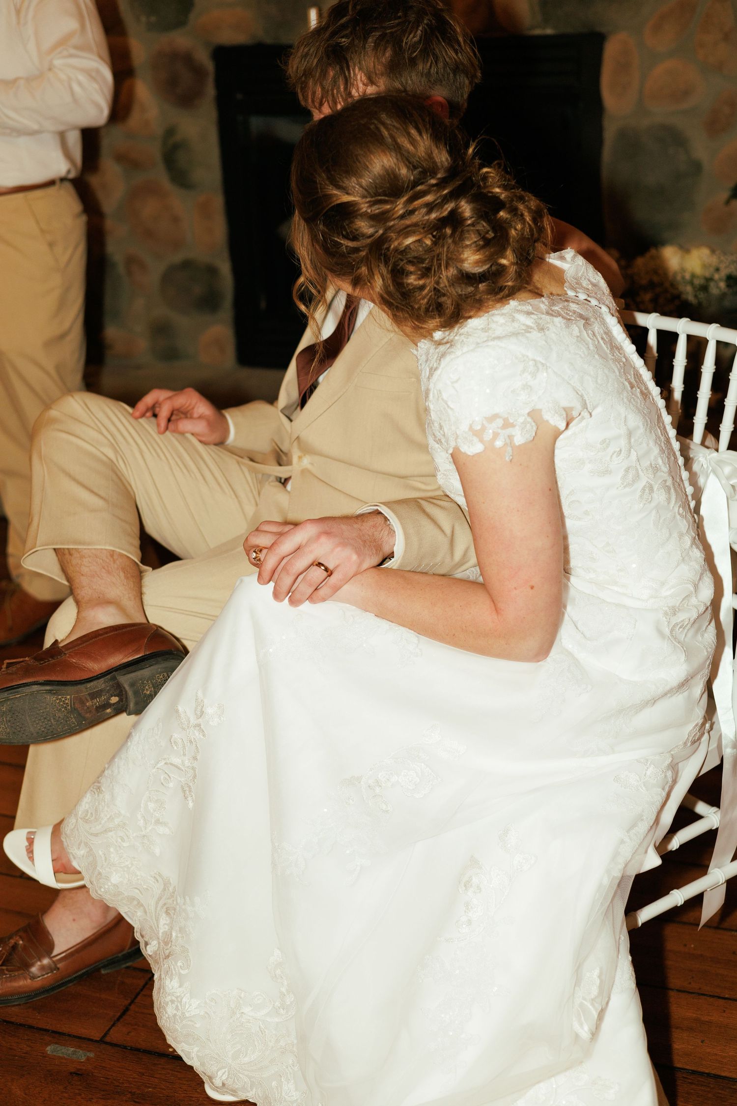 Close-up details of bride's lace dress during intimate moment at reception.