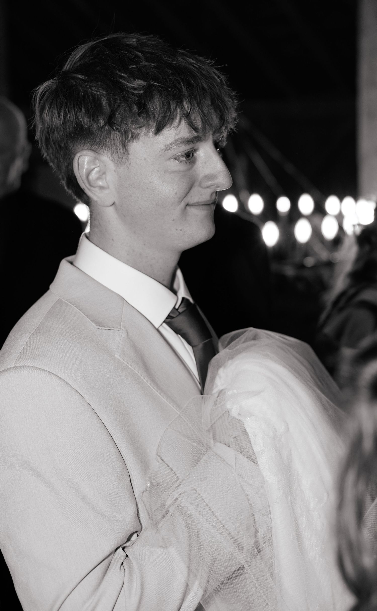 Side profile view of someone wearing a cream colored suit at an evening event.