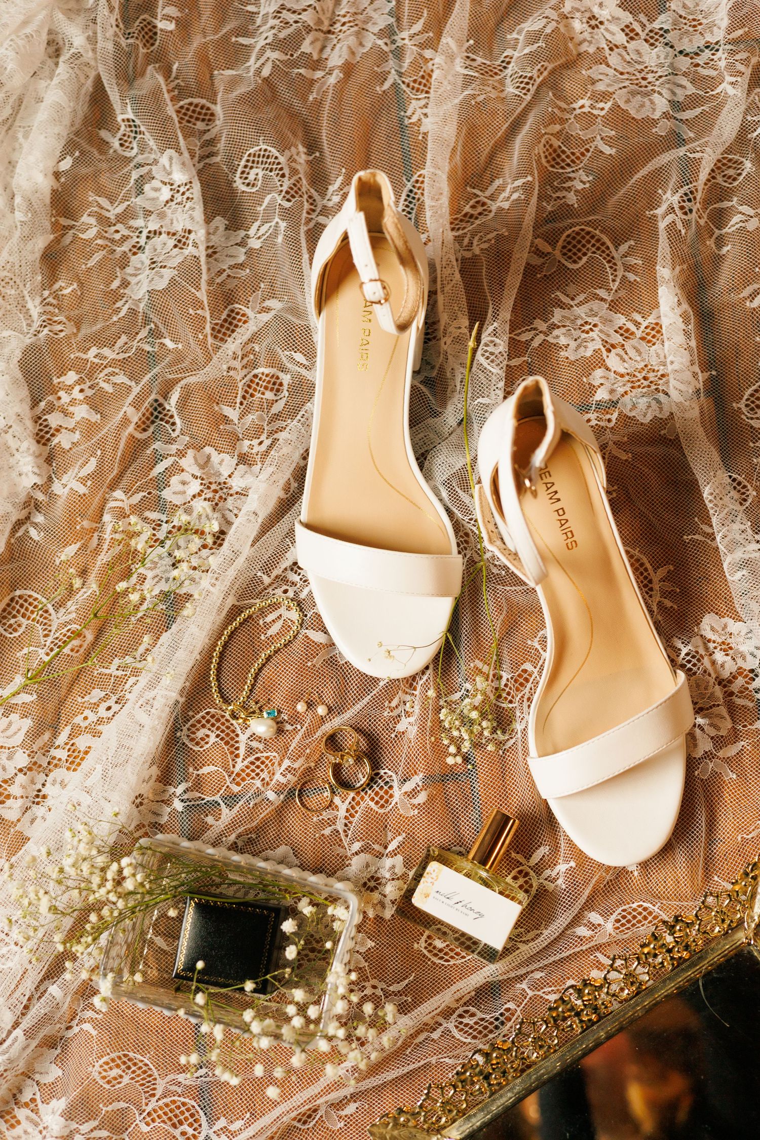 Elegant bridal shoes displayed against delicate lace fabric with baby's breath accents.