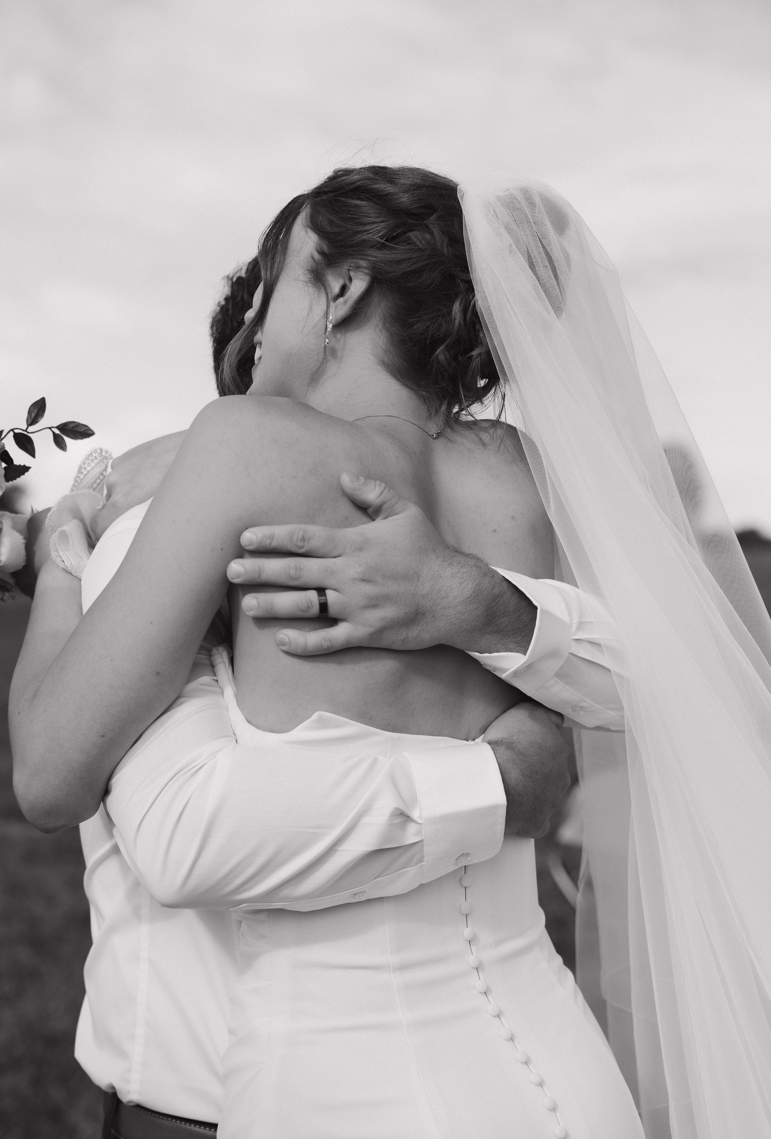 Black and white photo of a bride and groom sharing a romantic embrace on their wedding day.