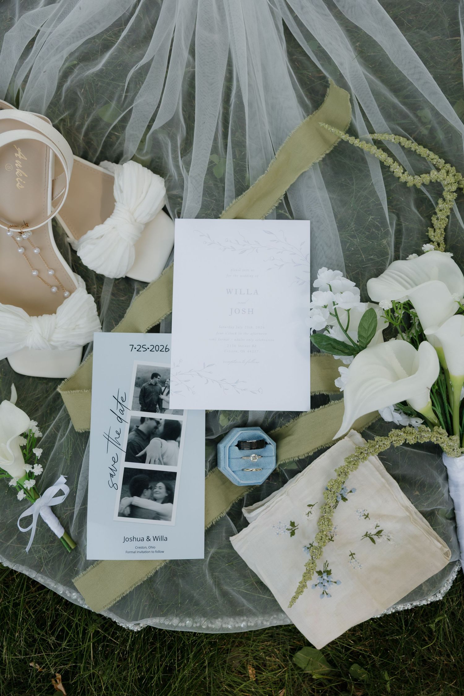 Flat lay of wedding details including veil, heels, rings, save the date, ceremony program, and white floral bouquet.