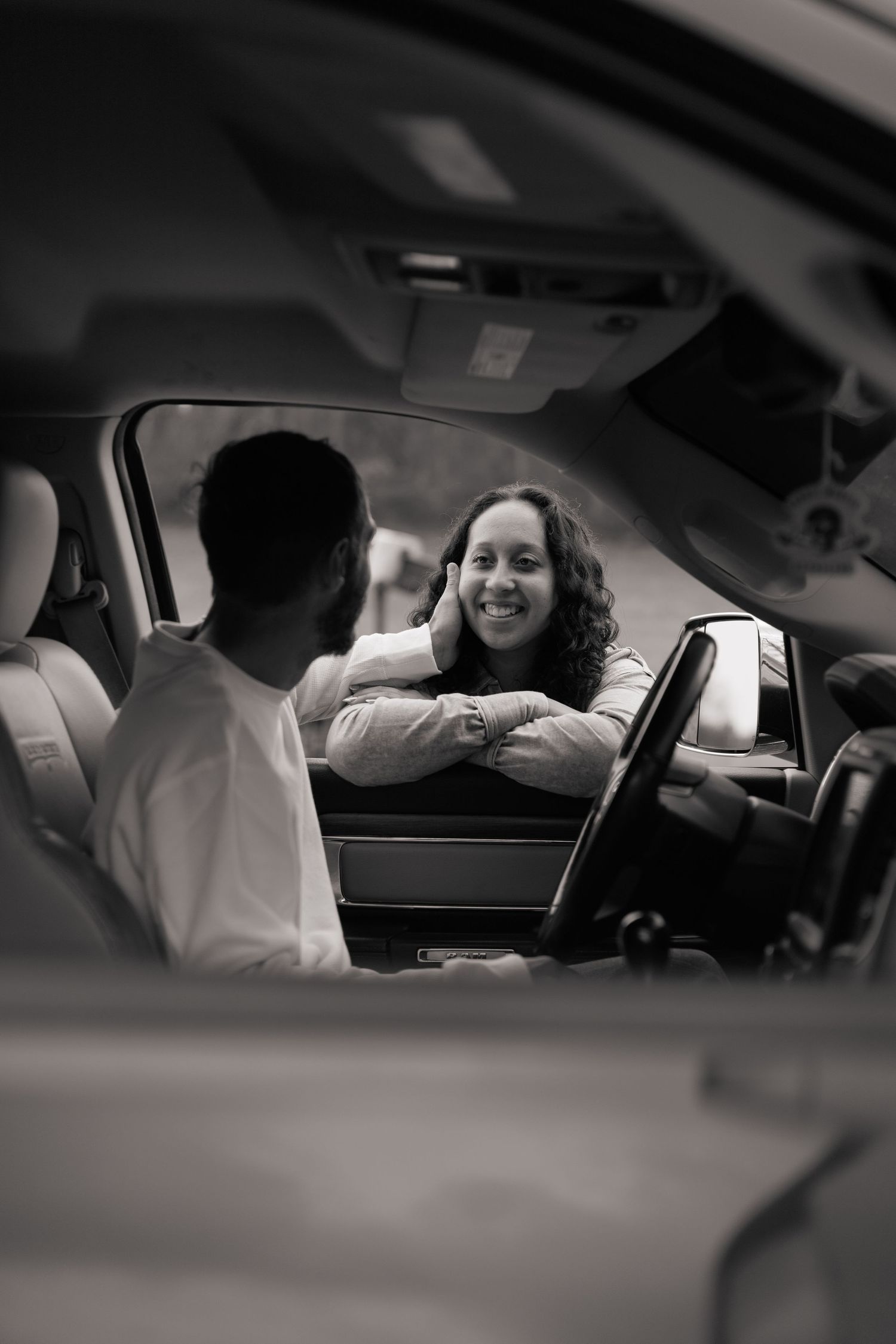 Black and white photo of passengers sharing laughter inside a car.