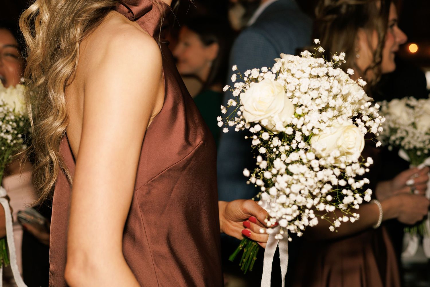 Wedding guests holding delicate baby's breath bouquets at an evening celebration.