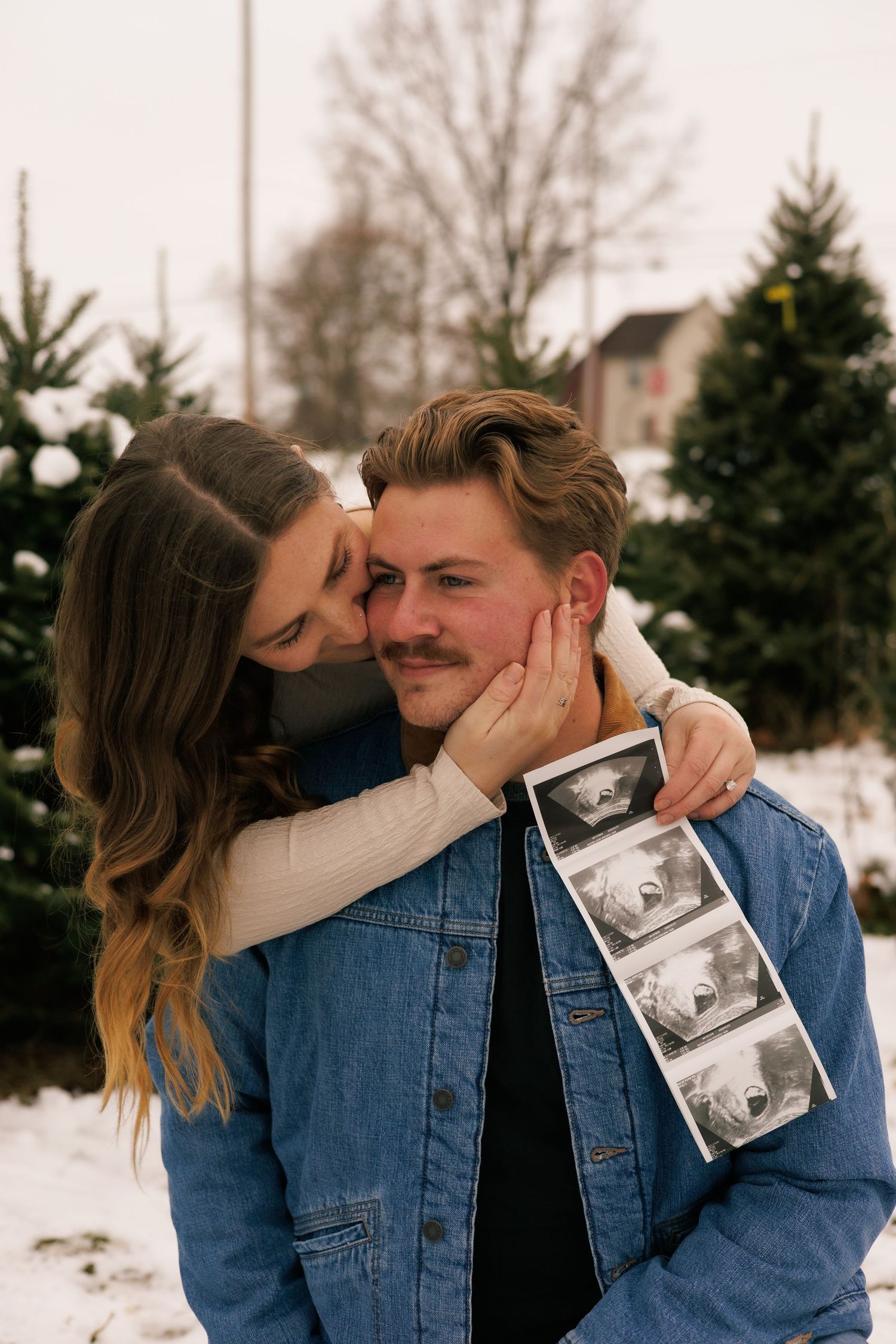 An emotional pregnancy reveal moment captured between a couple in the snow.