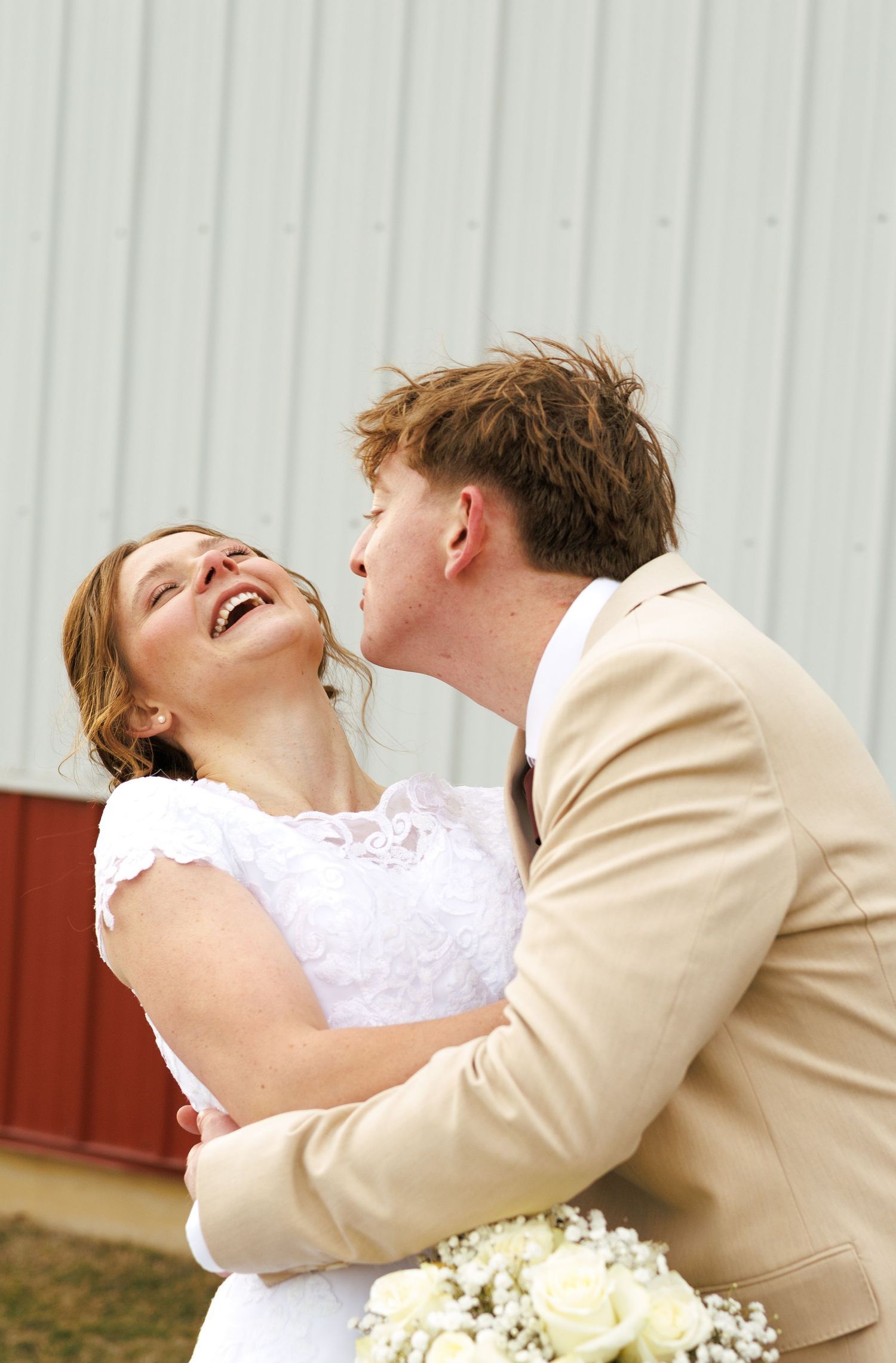 Newlyweds share a joyful moment together outdoors in formal wedding attire.