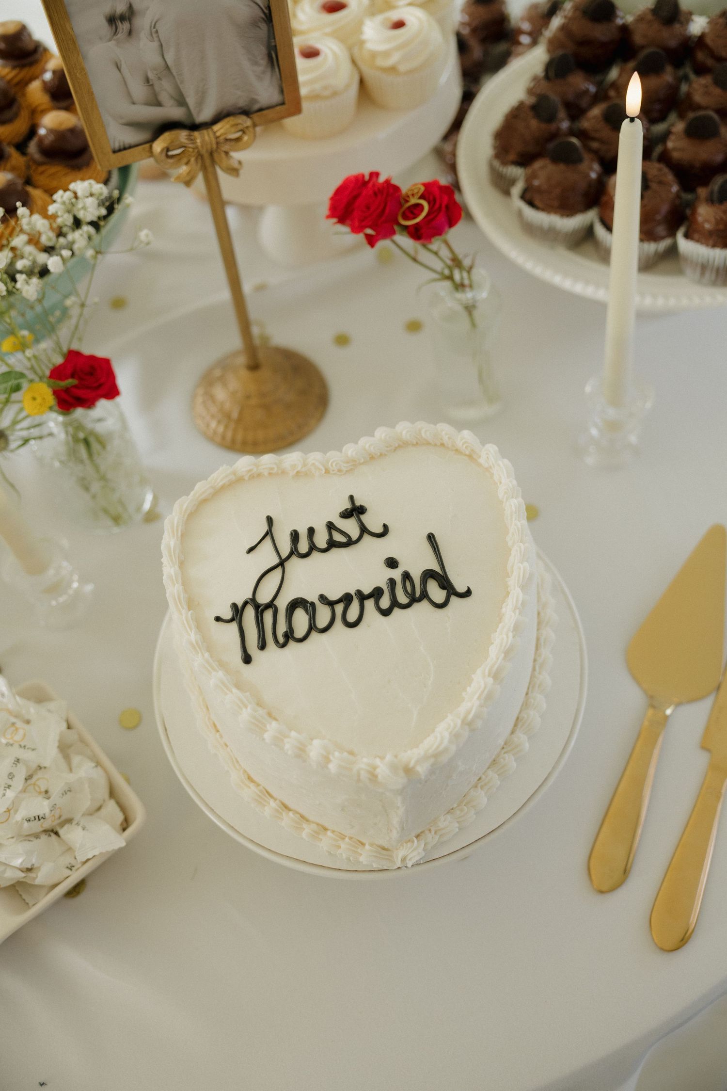 Heart-shaped white wedding cake inscribed with Just Married on a decorated dessert table.