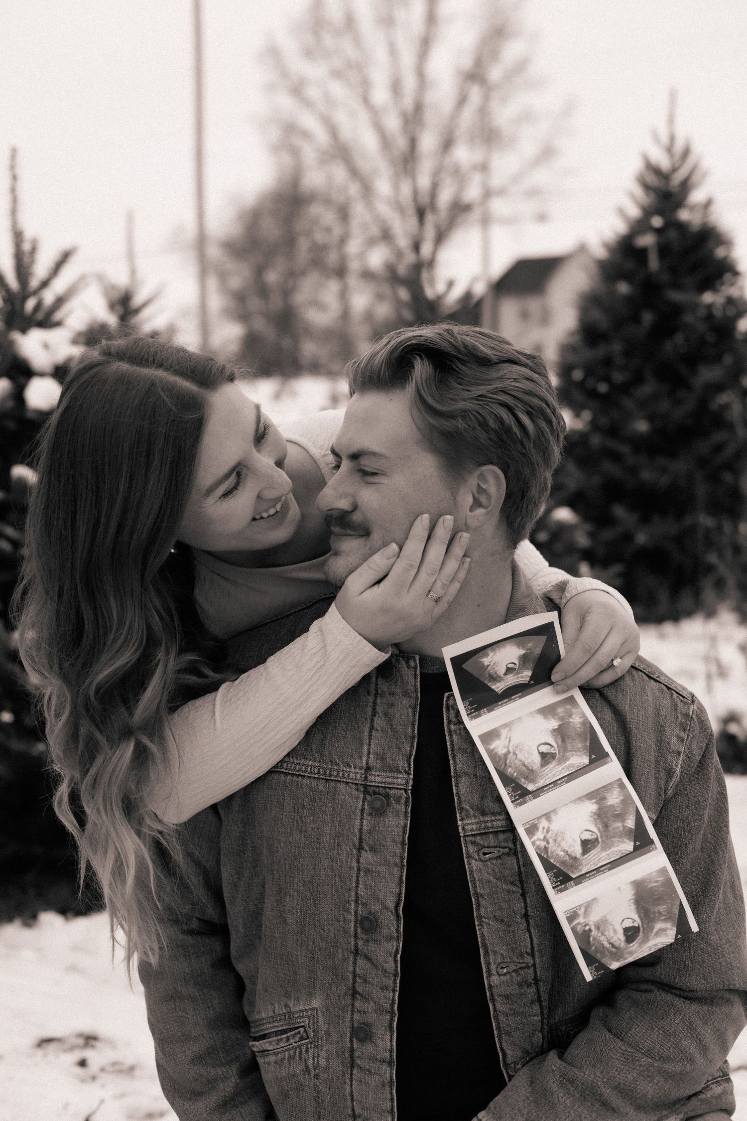 A tender moment between a couple sharing their pregnancy news in a winter setting.