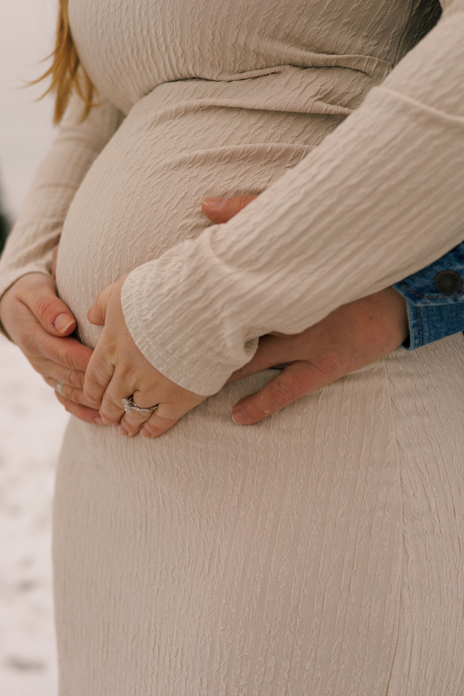 Close-up shots of hands resting on a pregnant belly wearing a cream textured sweater.