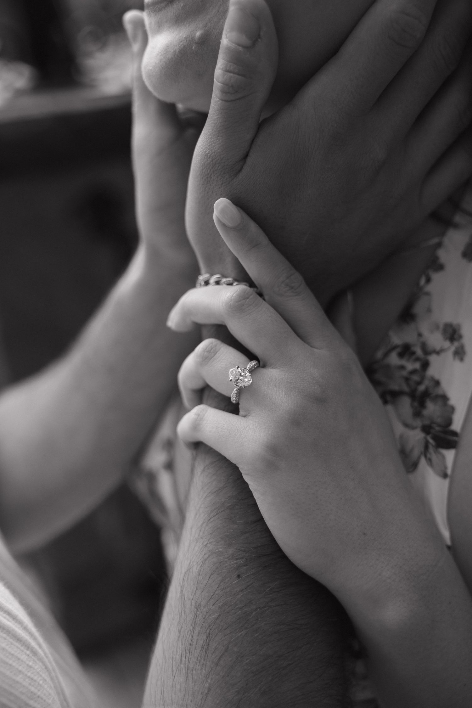 Black and white photo of hands touching, woman wearing a diamond engagement ring.