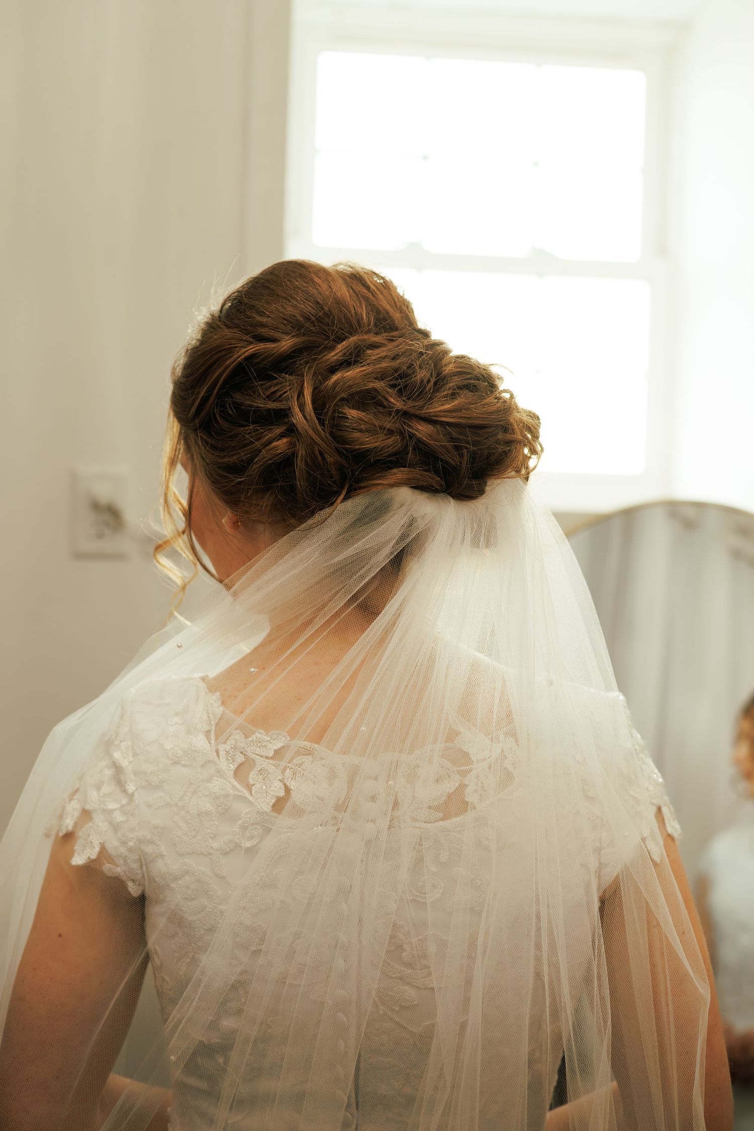 Back view of a bride wearing a white lace wedding dress with a flowing veil.