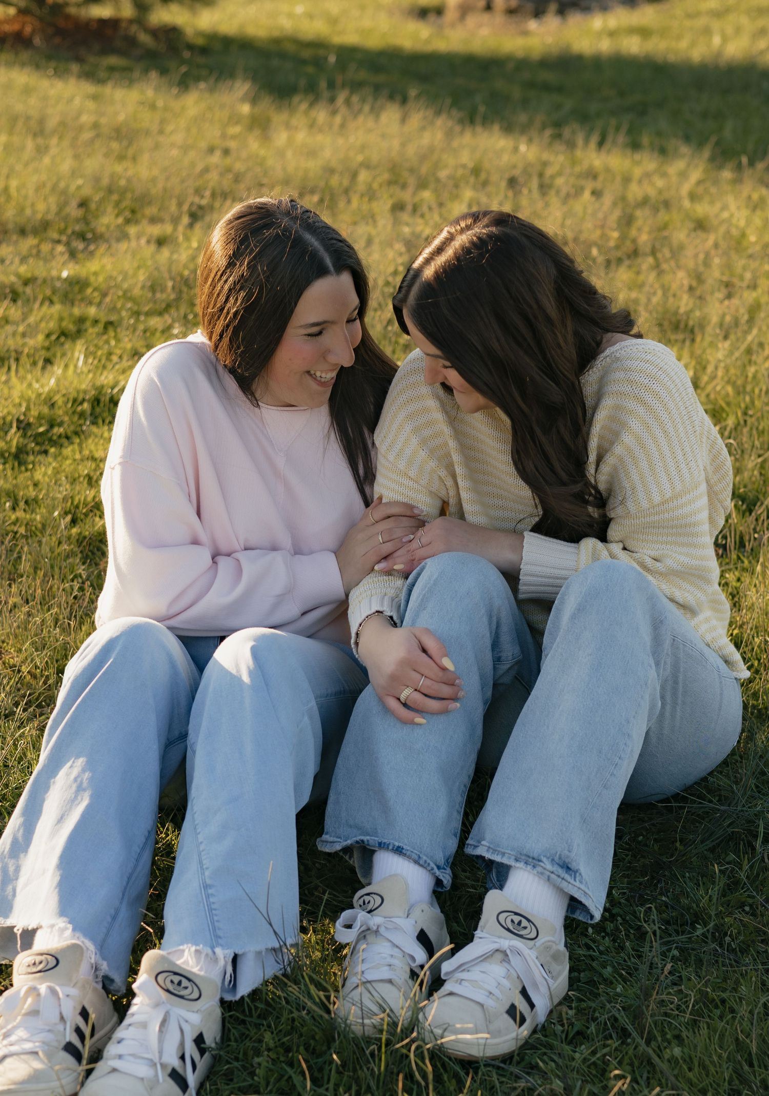 A sequence of tender moments between two people sitting close together on grassy ground in warm sunlight.