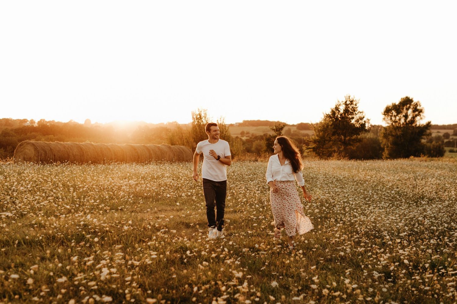 Séance de couple, amoureux courant dans un champ de fleurs au coucher du soleil dans le Tarn