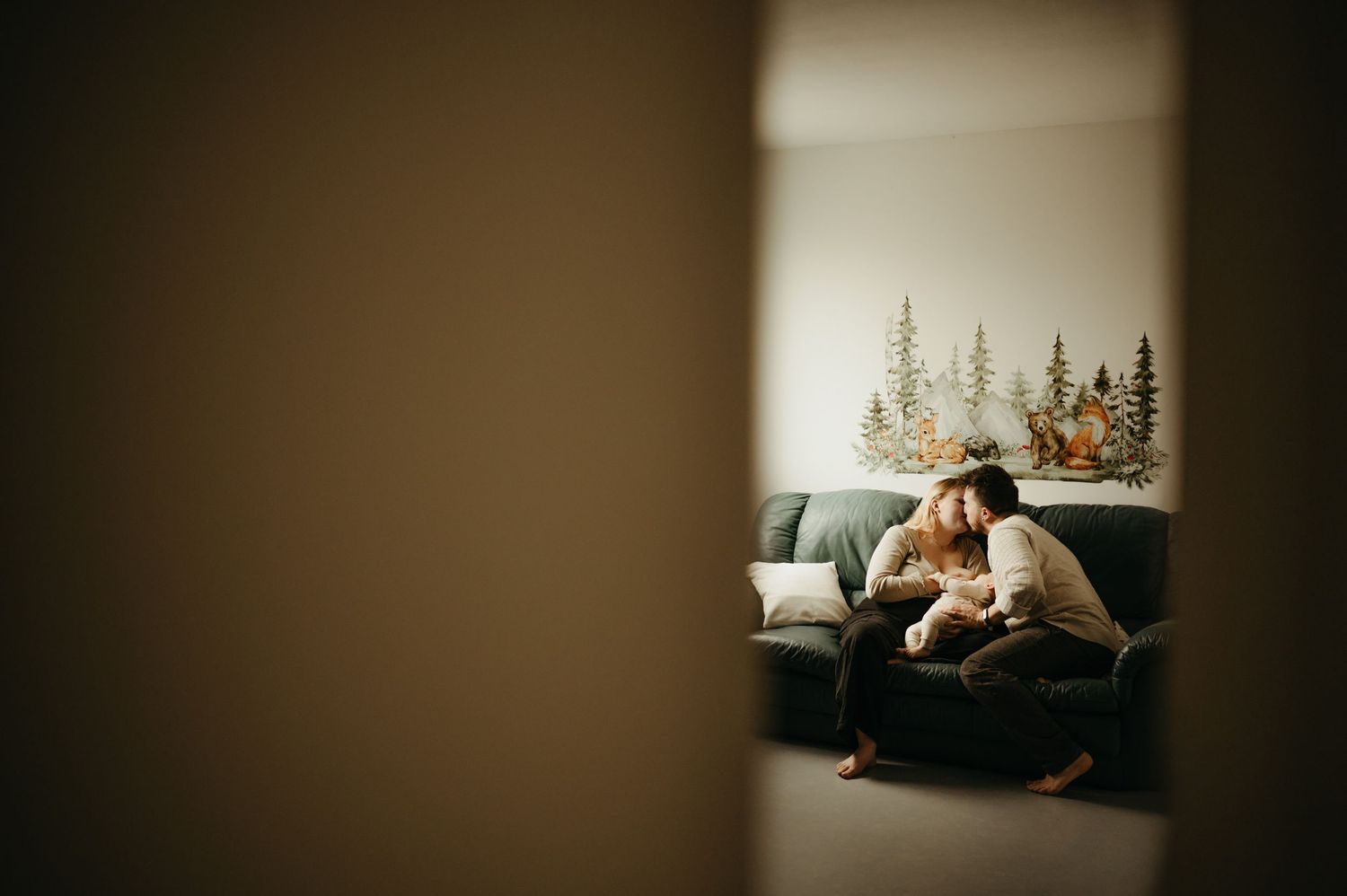 Séance allaitement intimiste à domicile, les parents s'embrassant sur le canapé pendant que bébé est endormi