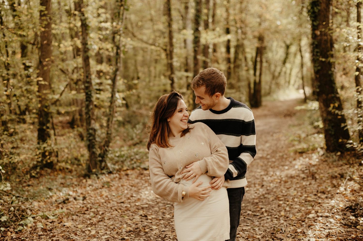 Séance grossesse, futurs parents s'enlaçant en souriant, en extérieur dans la nature à Gaillac