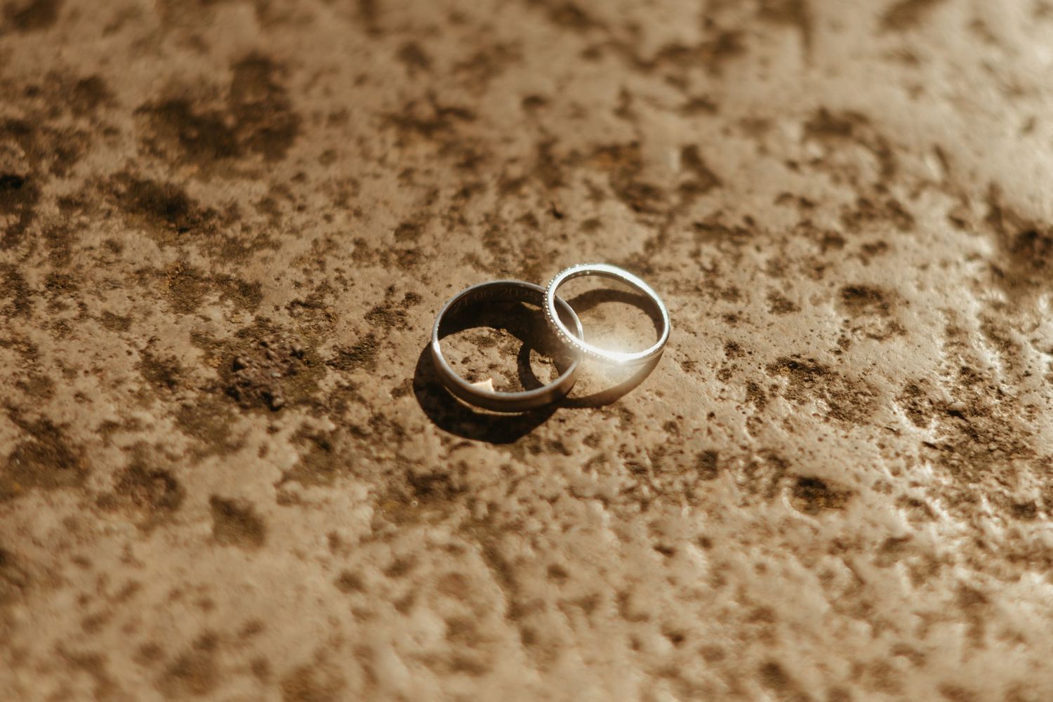 Détail d'alliances posées sur de la pierre, dans des tons naturels et chaleureux, d'un mariage à Lavaur