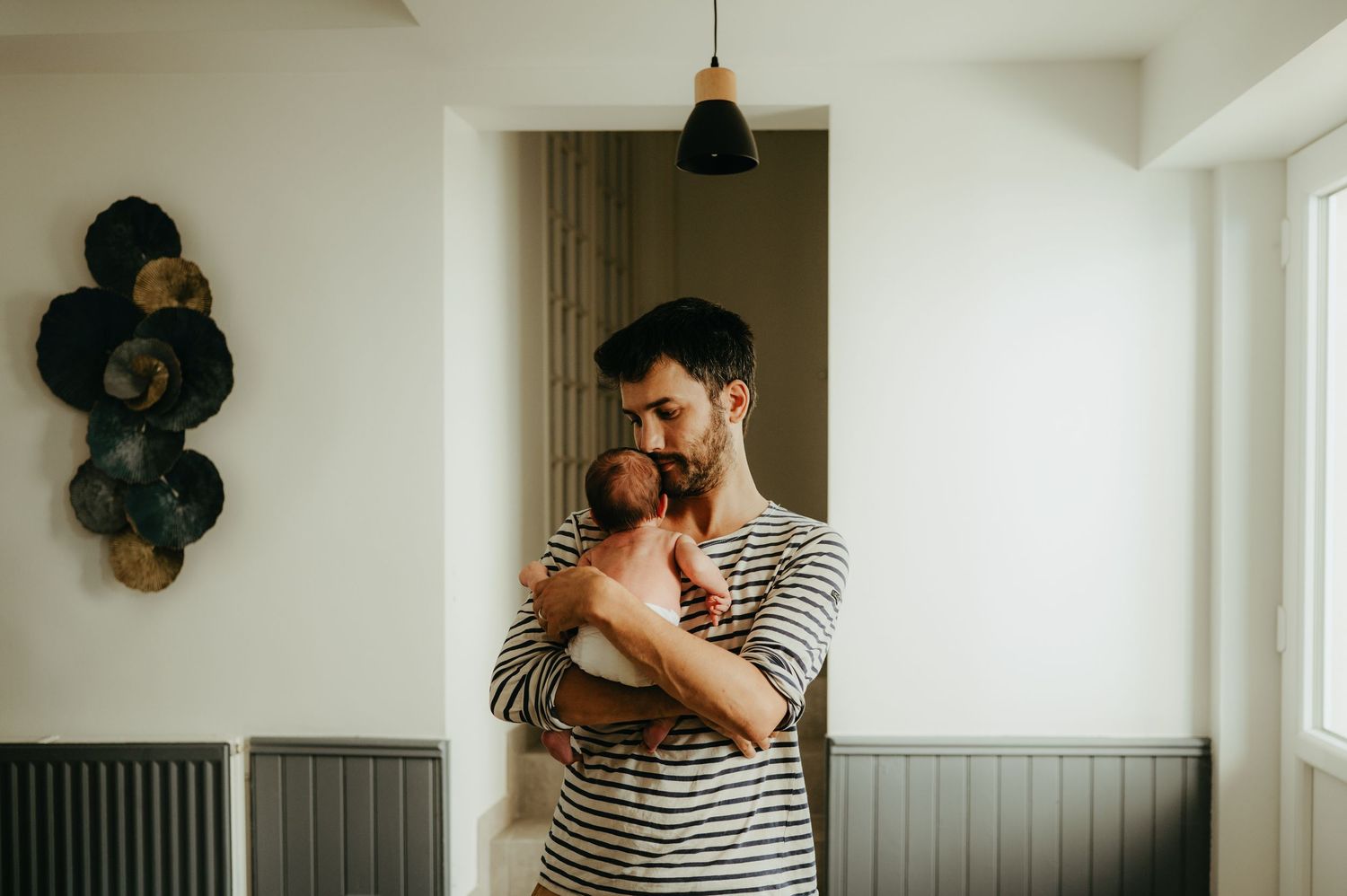 Séance naissance, papa prend bébé dans ses bras pour la réconforter, à son domicile à Bessières