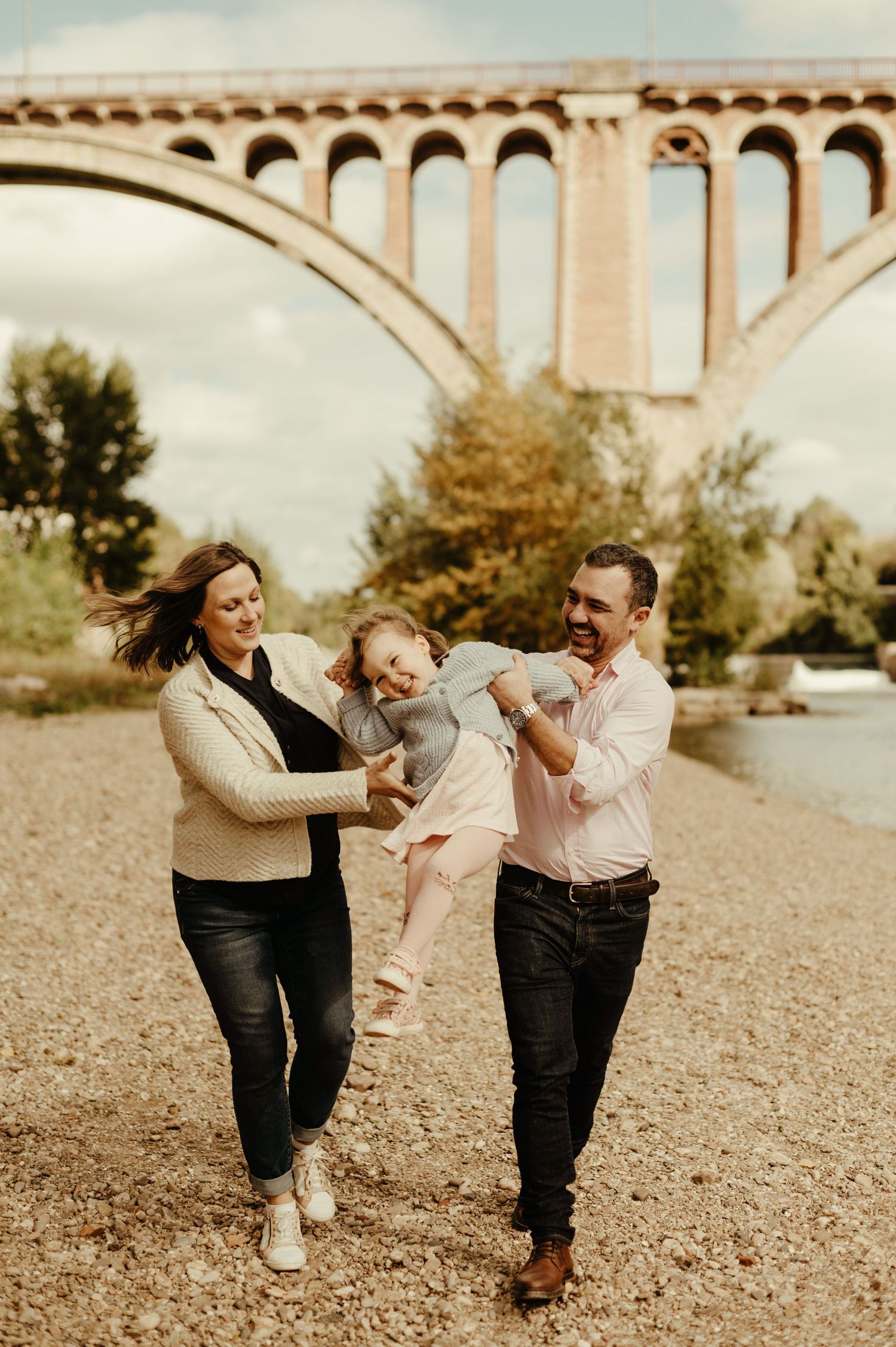 Séance maternité, les parents jouant avec leur premier enfant au bord de la rivière, sous le pont de Rabastens