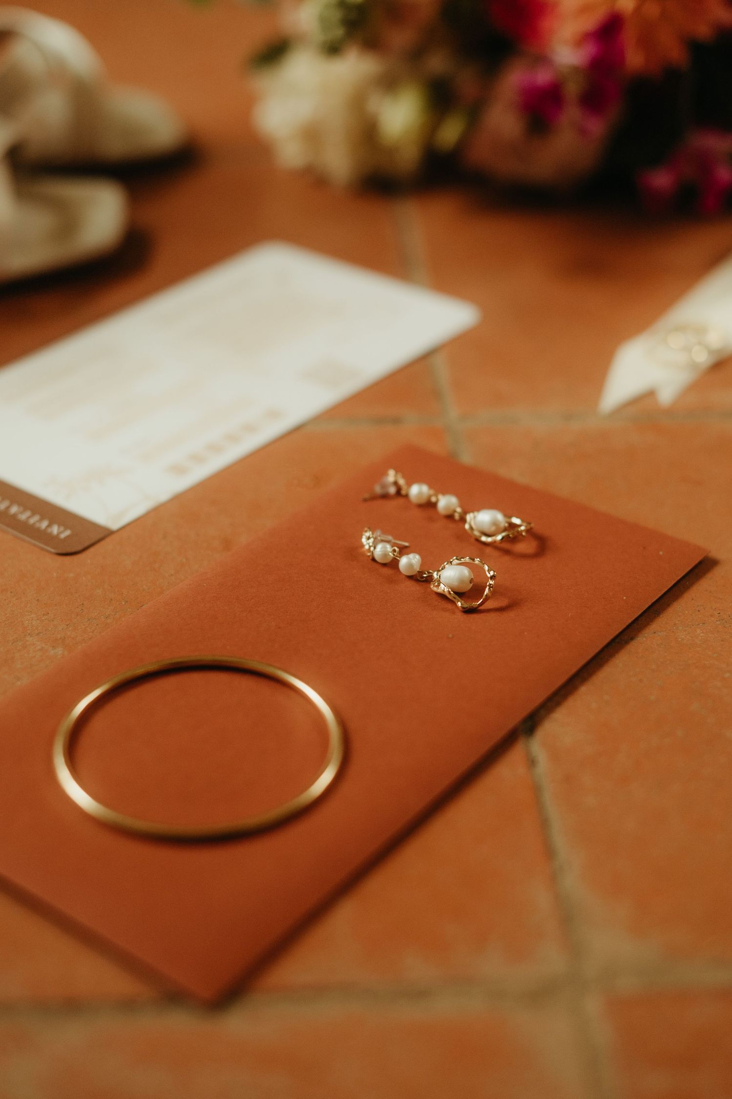 Bijoux de mariée, posés sur une enveloppe terracotta sur de la tomette typique du Tarn