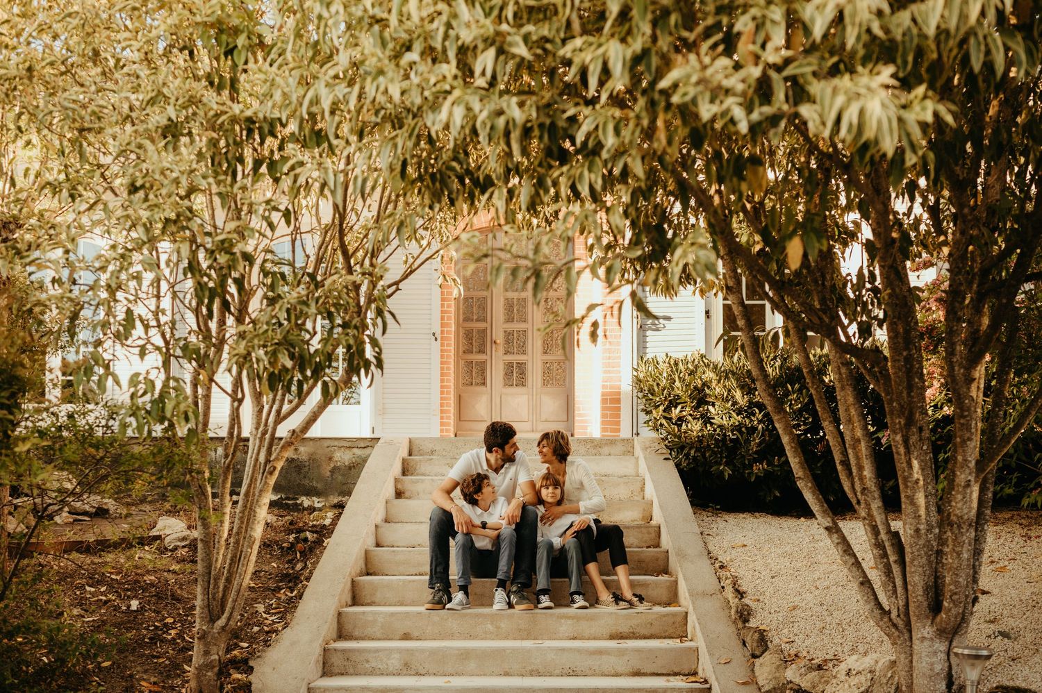 Famille assise sur les escaliers devant leur maison, à la fin du printemps à Lavaur