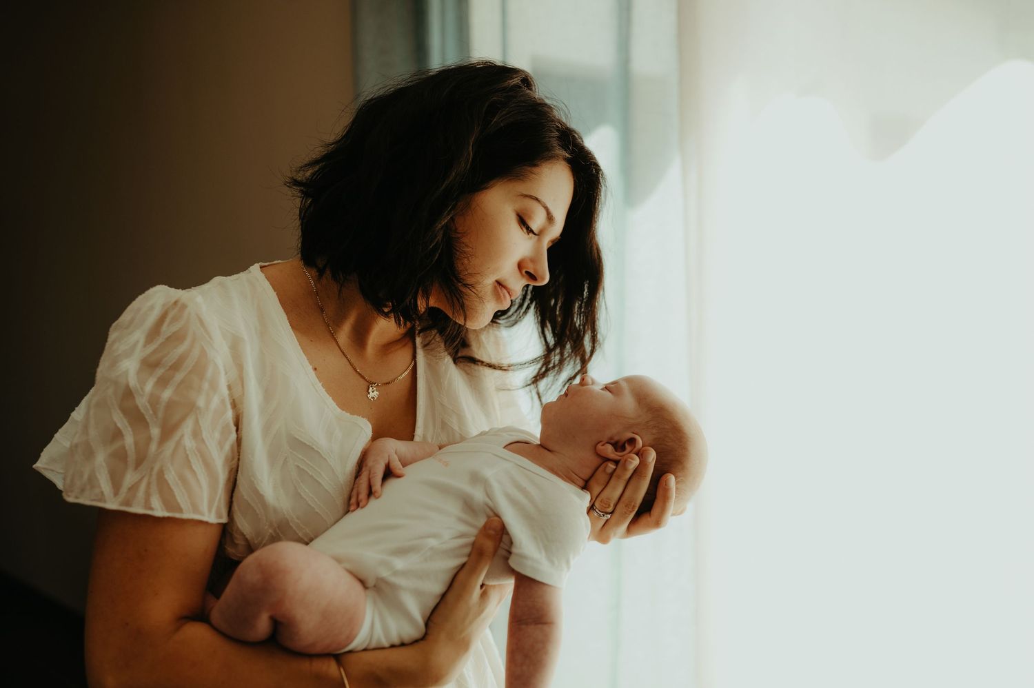 Séance naissance, une maman tient et regarde tendrement son bébé endormi à Buzet sur Tarn
