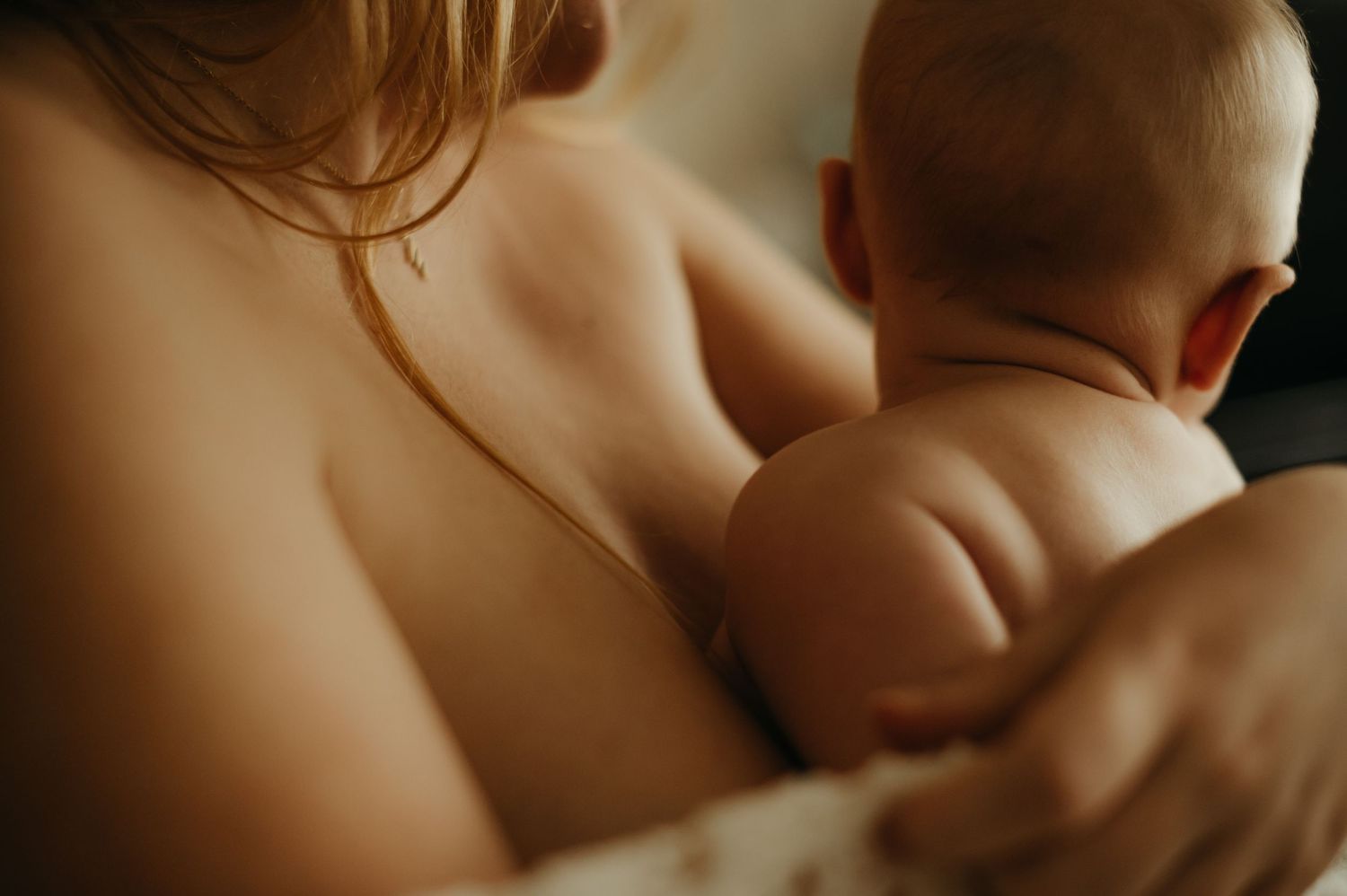 Détail de séance naissance, bébé en peau à peau contre sa maman, dans des tons chaleureux à Saint Lieux les Lavaur