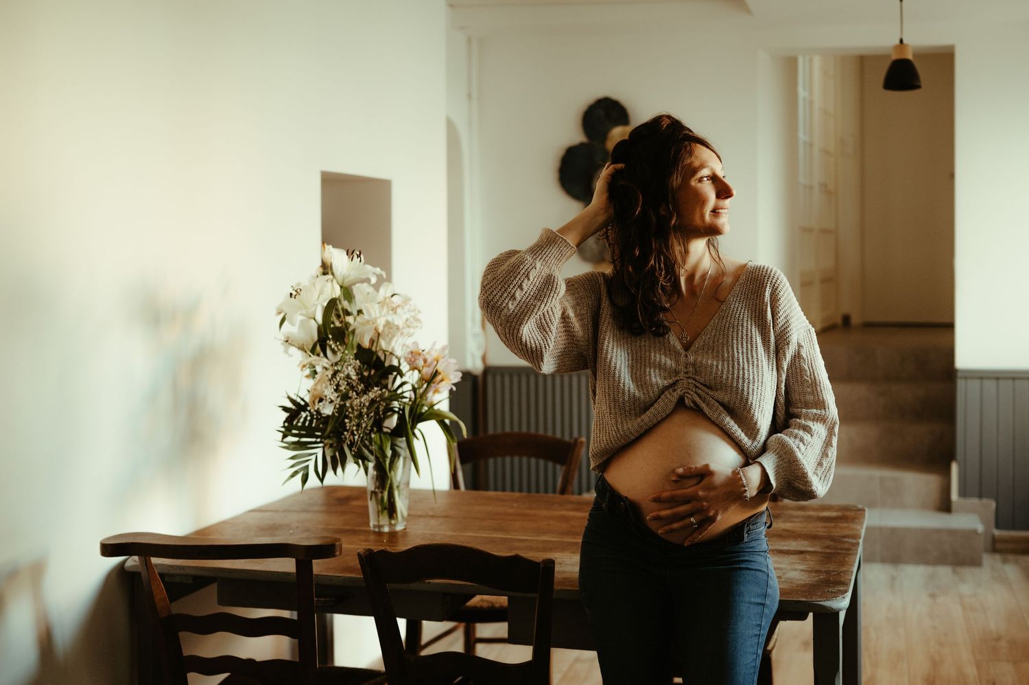 Séance maternité, future maman chez elle, main sur son ventre rond, à Lisle sur Tarn