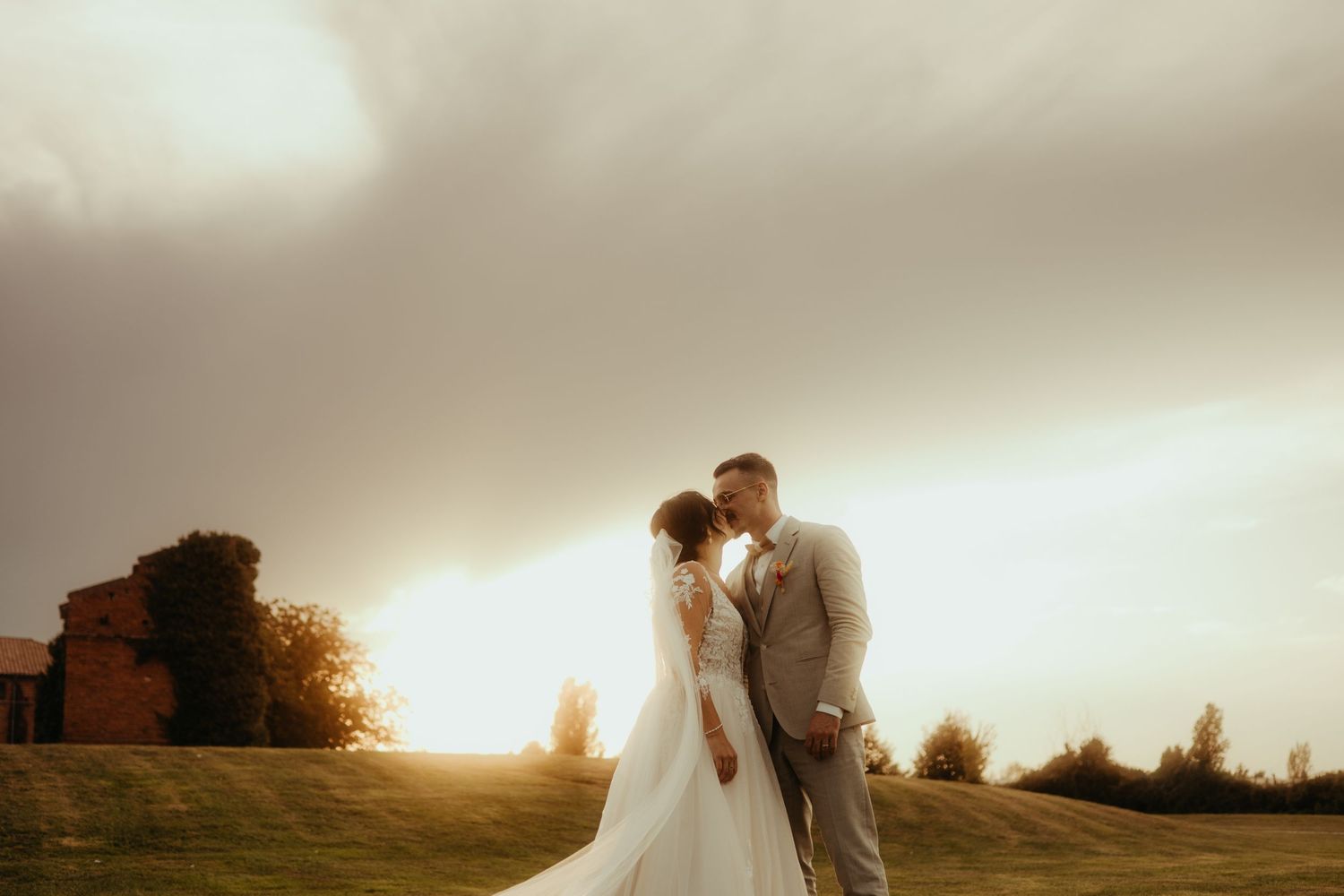 Couple s'embrassant pendant leur mariage, au coucher de soleil, avec des nuages orageux, près de Montauban