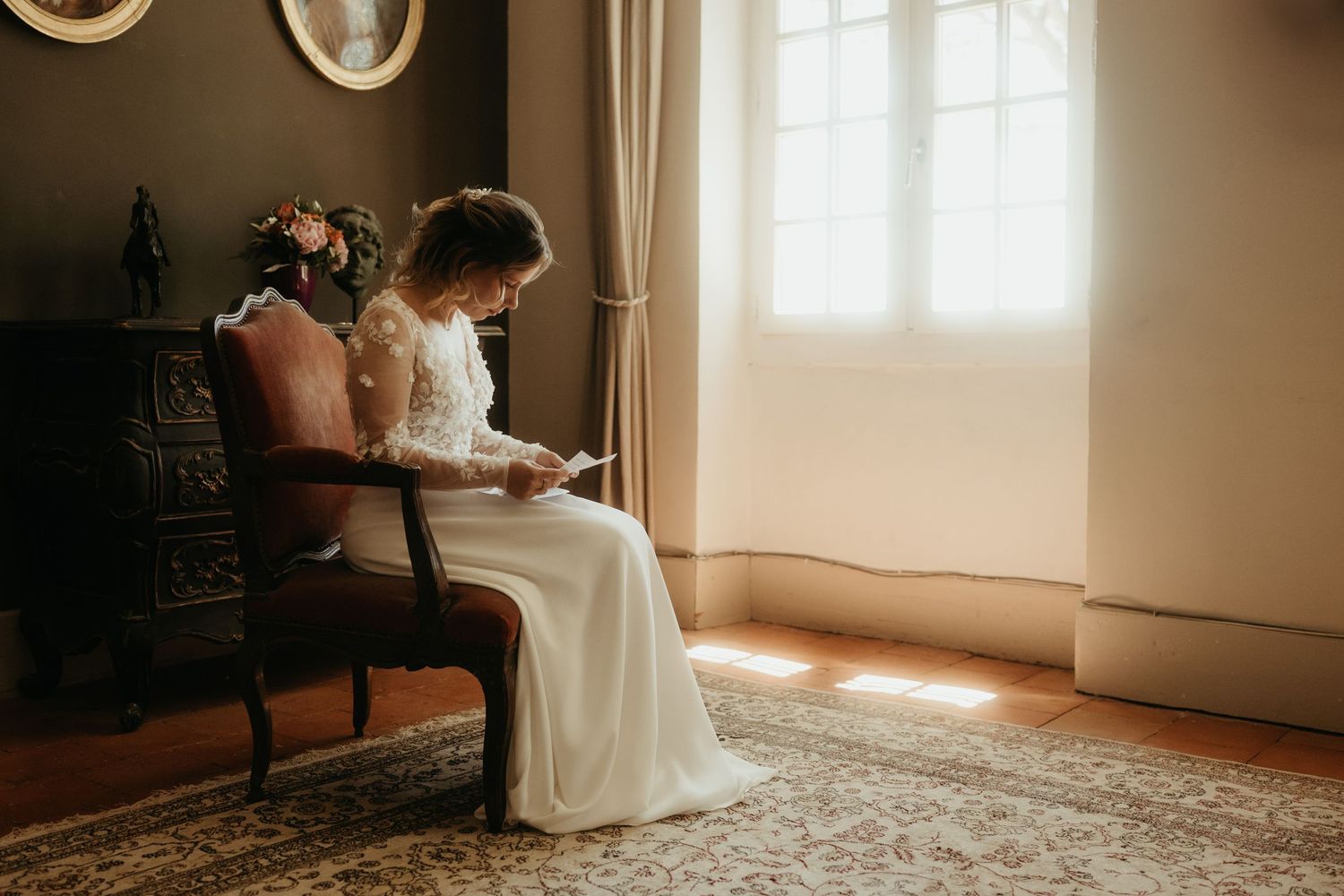 Mariée émue lisant une lettre de son époux, avec un rayon de soleil dans la chambre, au Domaine de la Bouriette à Castres