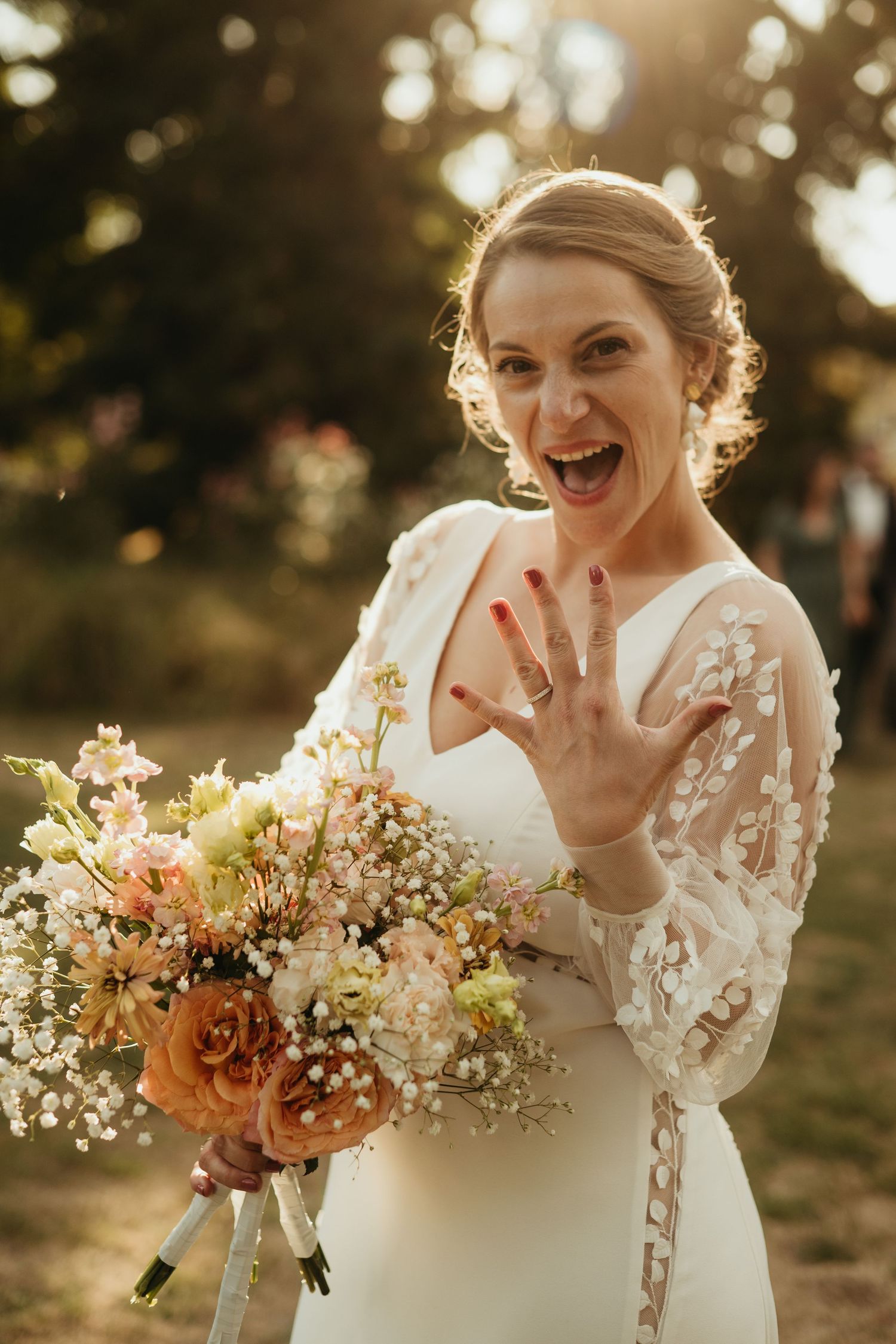 Mariée au coucher du soleil, montrant fièrement sont alliance, sa belle robe en dentelle 3D et son bouquet en Nouvelle Aquitaine