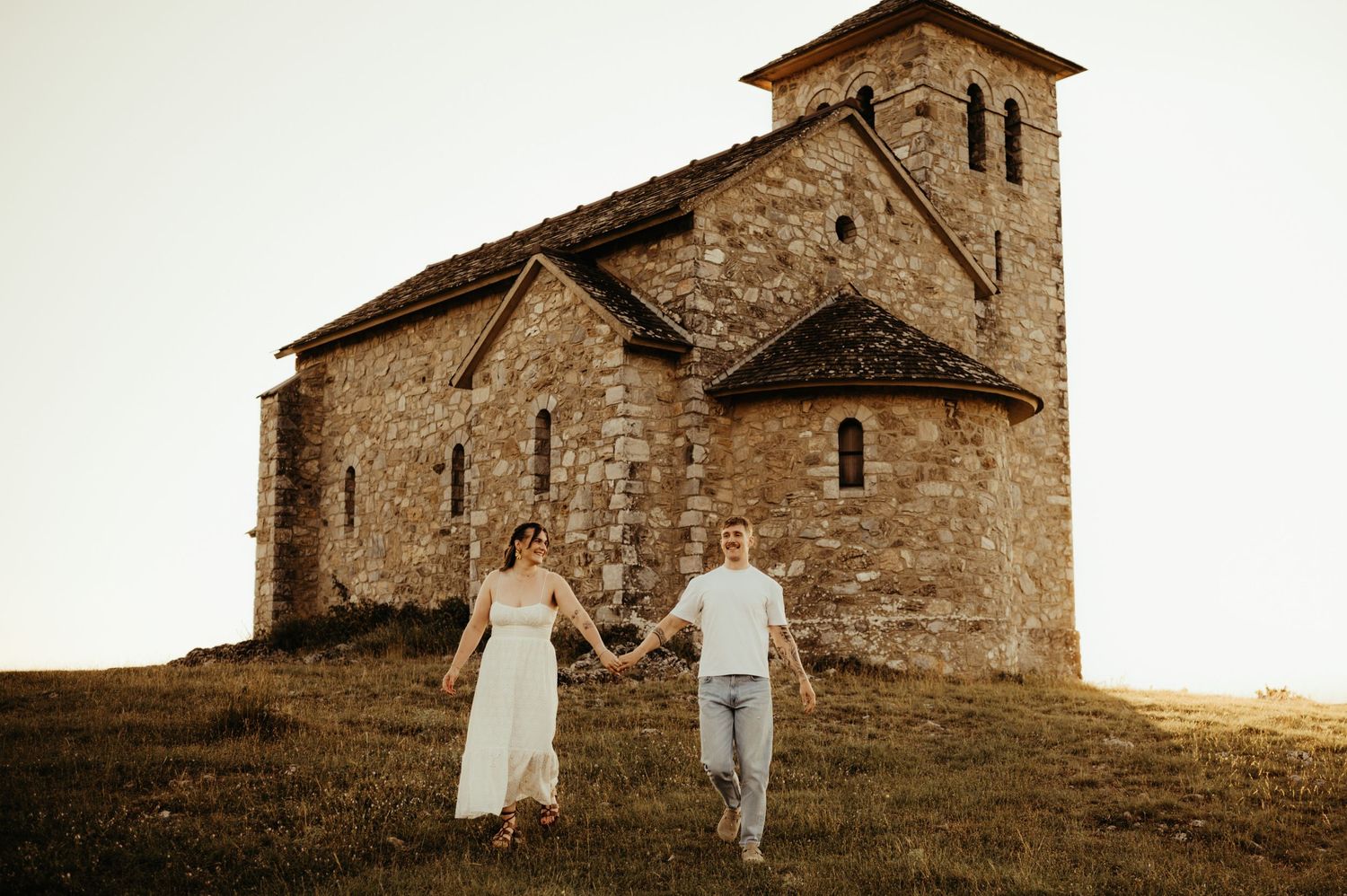 Séance couple en extérieur devant une chapelle en montagne au coucher du soleil à Dourgne