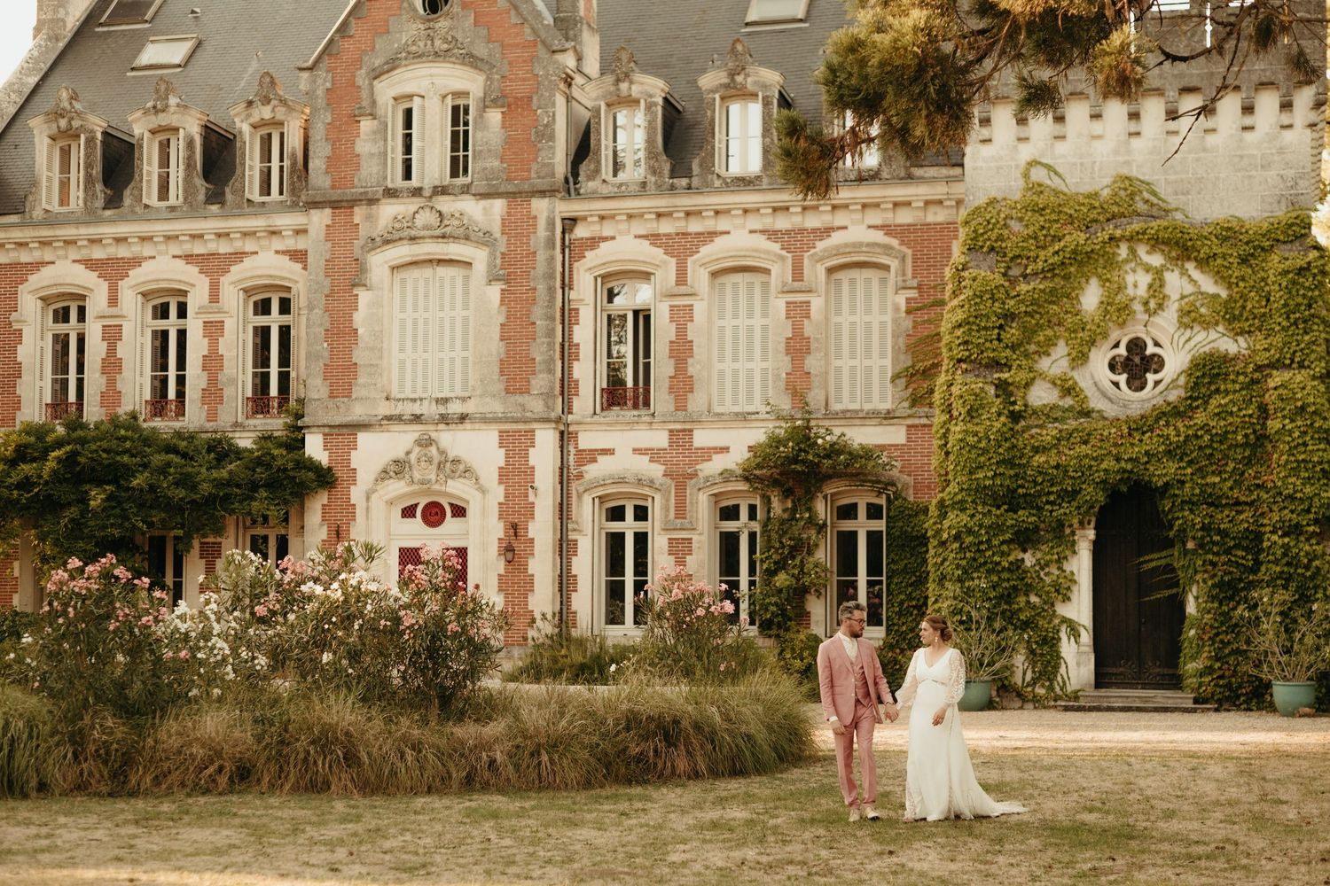 Mariés se promenant pendant la séance photo de couple, devant le château de la Pouyade en Charente