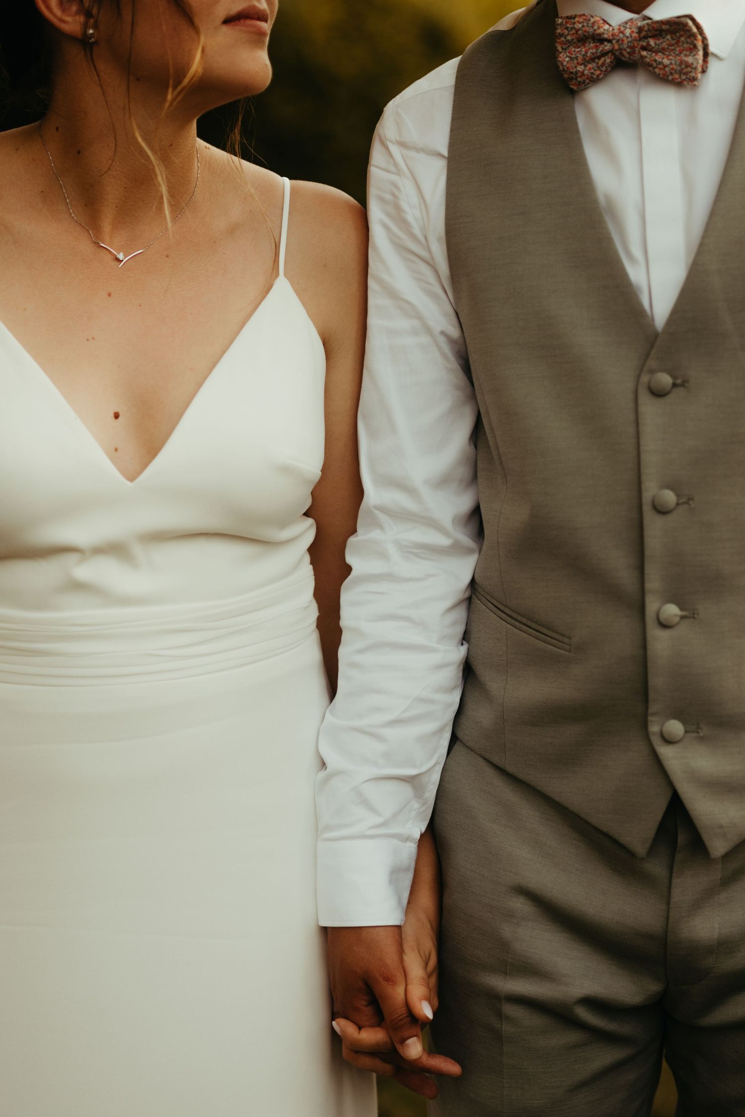 Détail de tenues de mariés, se tenant la main, pendant la séance photo de couple