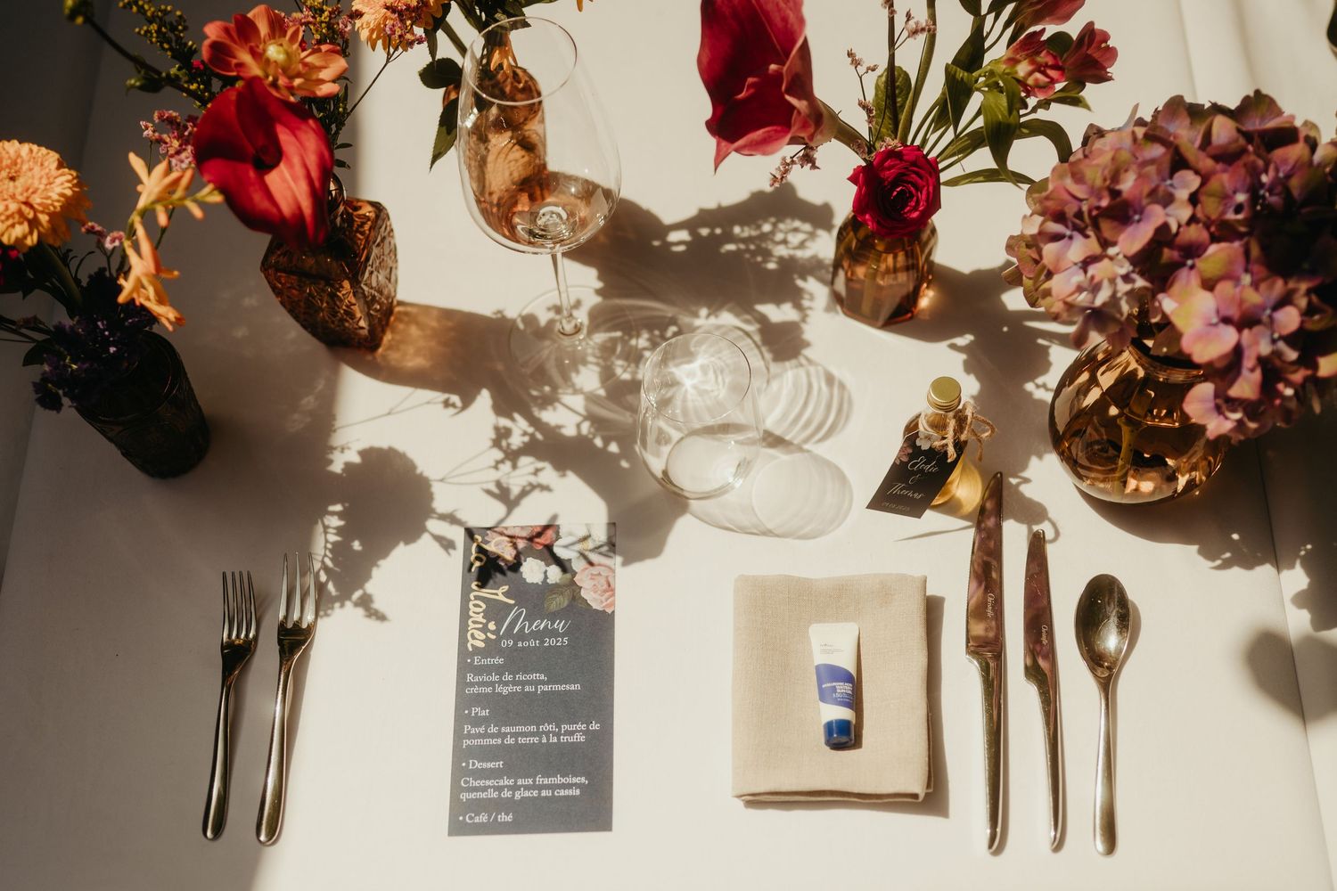 Détail de table de repas de mariage en extérieur, dressée avec des fleurs colorées dans des soliflores, au Restaurant Brut à Tournefeuille