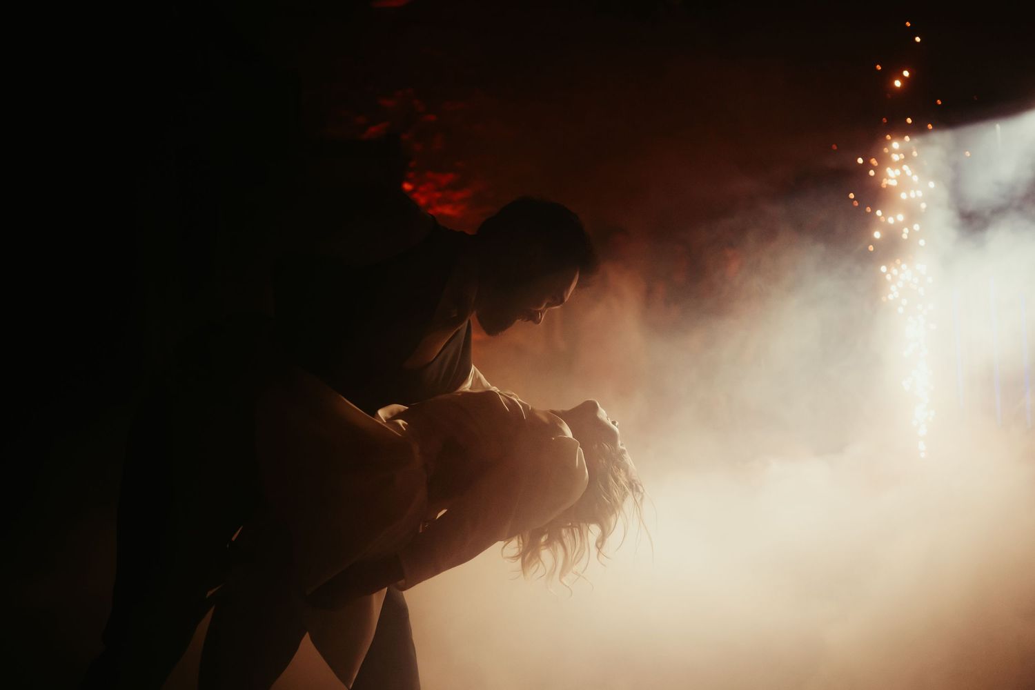 Ouverture de bal de soirée de mariage, les mariés dansant à la lumière des feux d'artifice transperçant la fumée, en Haute Garonne
