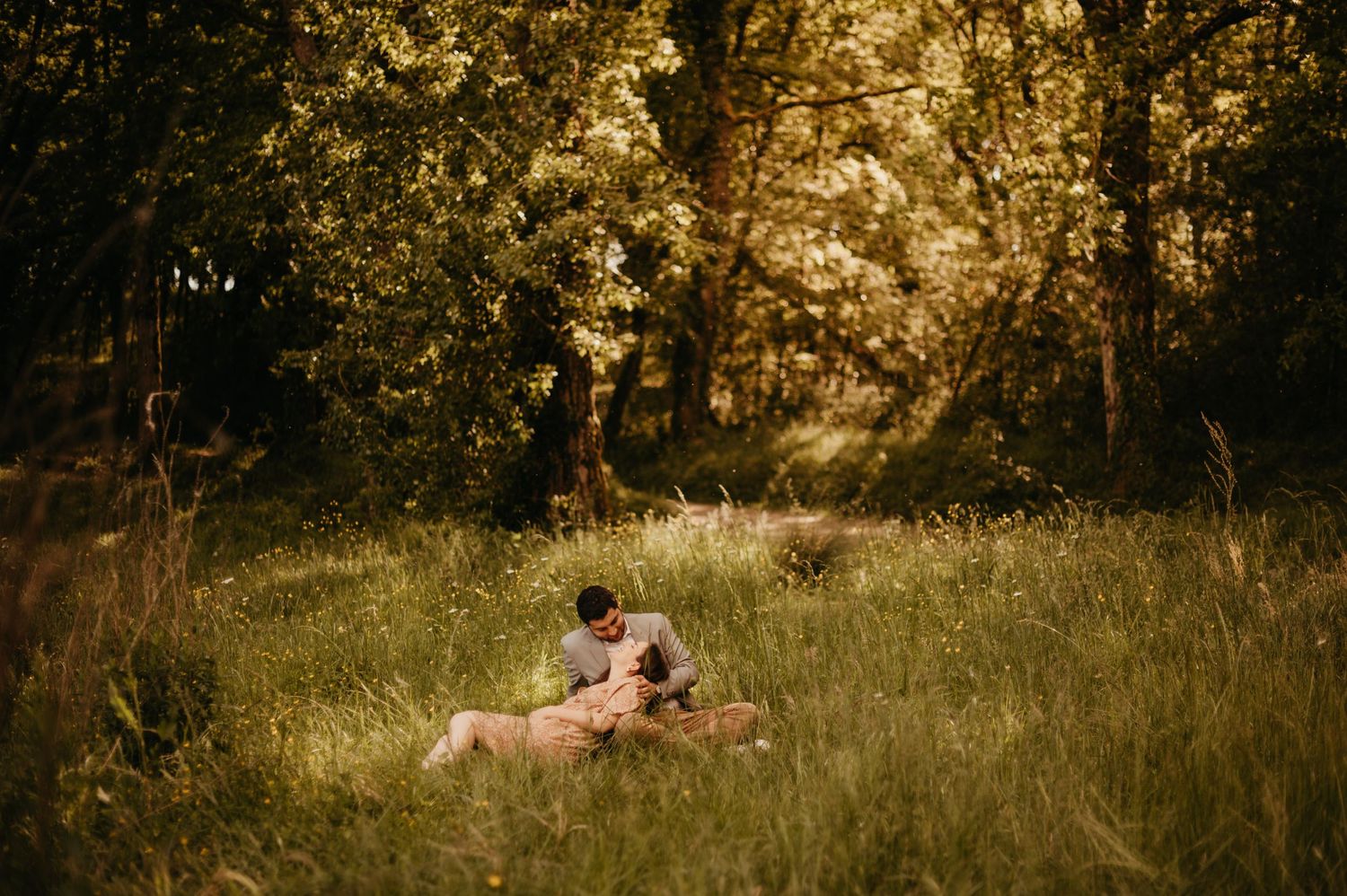 Séance maternité en forêt, futurs parents allongés dans l'herbe dans un moment naturel à Rabastens