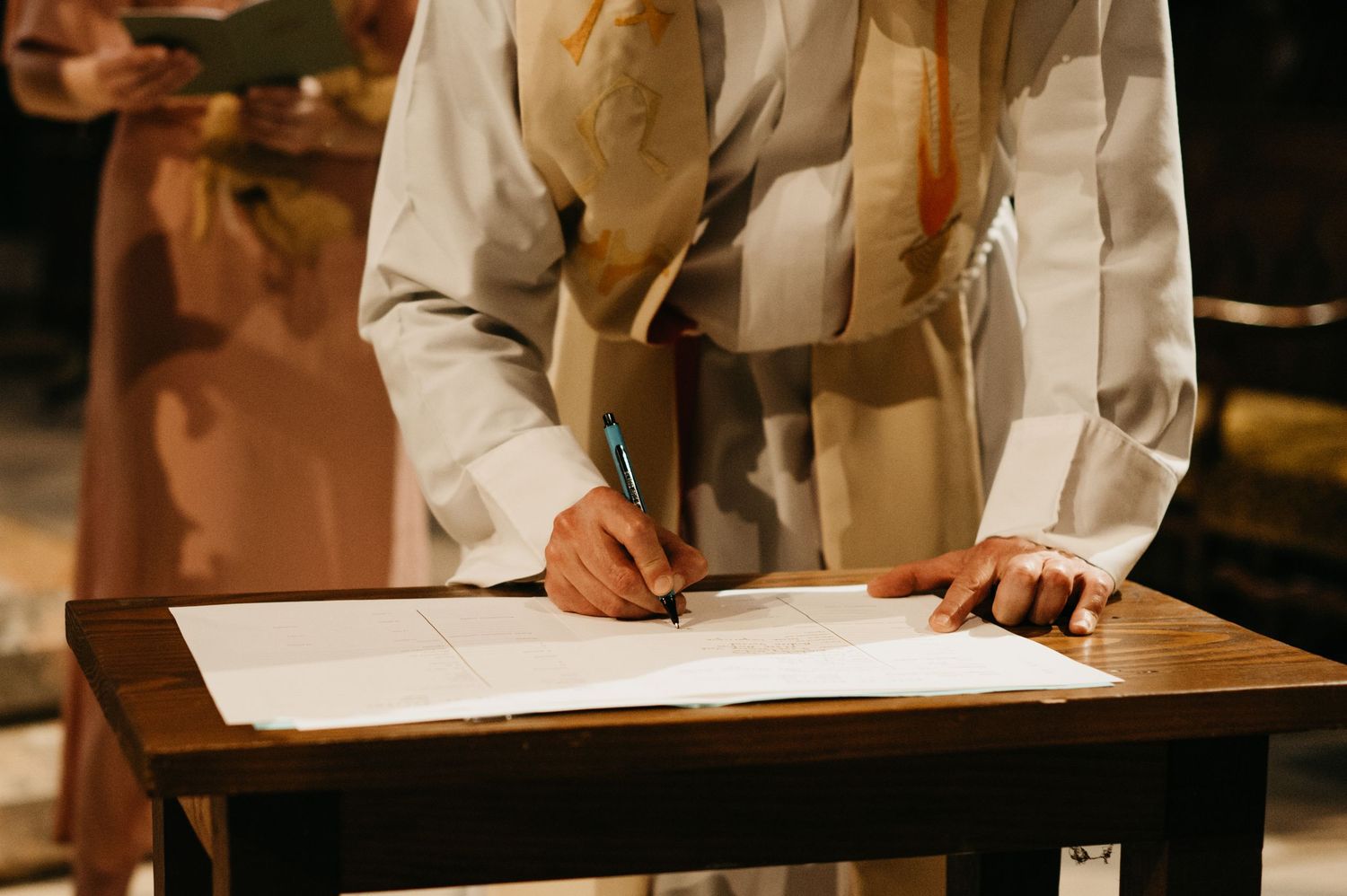 Prêtre signant un registre pendant un reportage baptême à Saint Sulpice