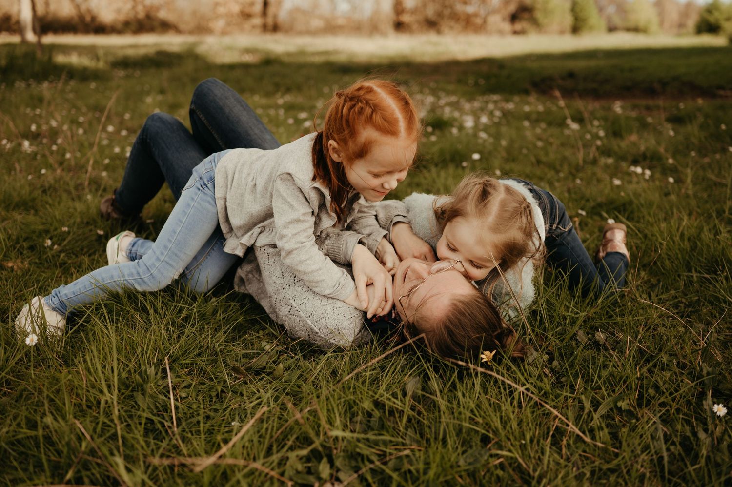 Séance famille : maman et ses filles jouant dans l'herbe, en riant, à Ludolac à Saint Lieux les Lavaur