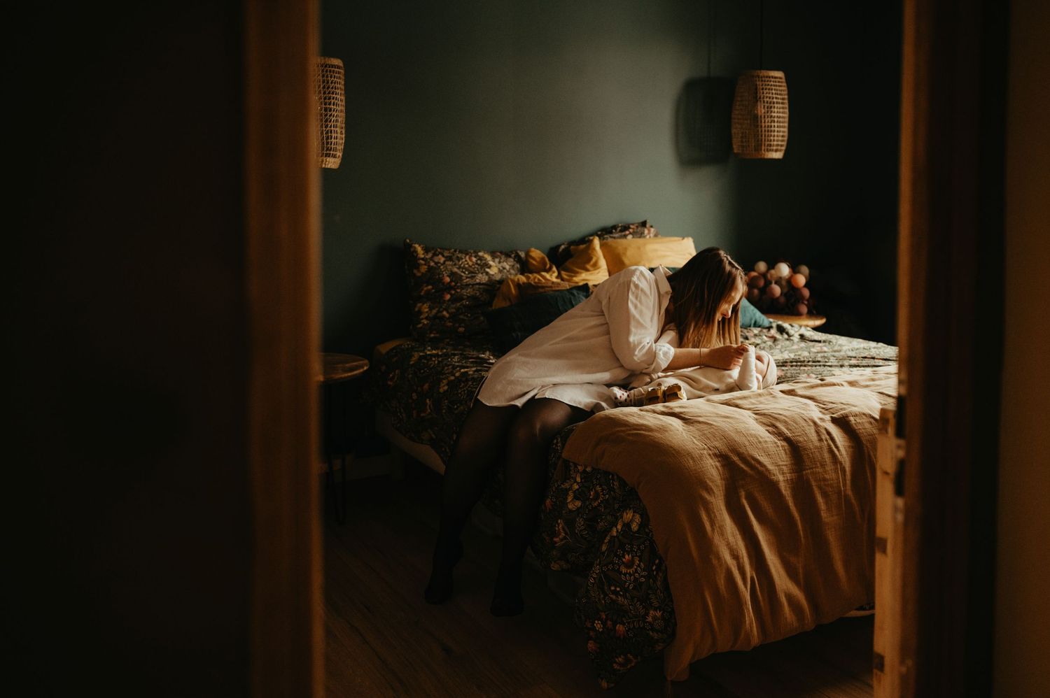 Bébé de 2 mois qui joue avec sa maman sur le lit, scène dans un cadre de porte avec des couleurs chaleureuses à Albi
