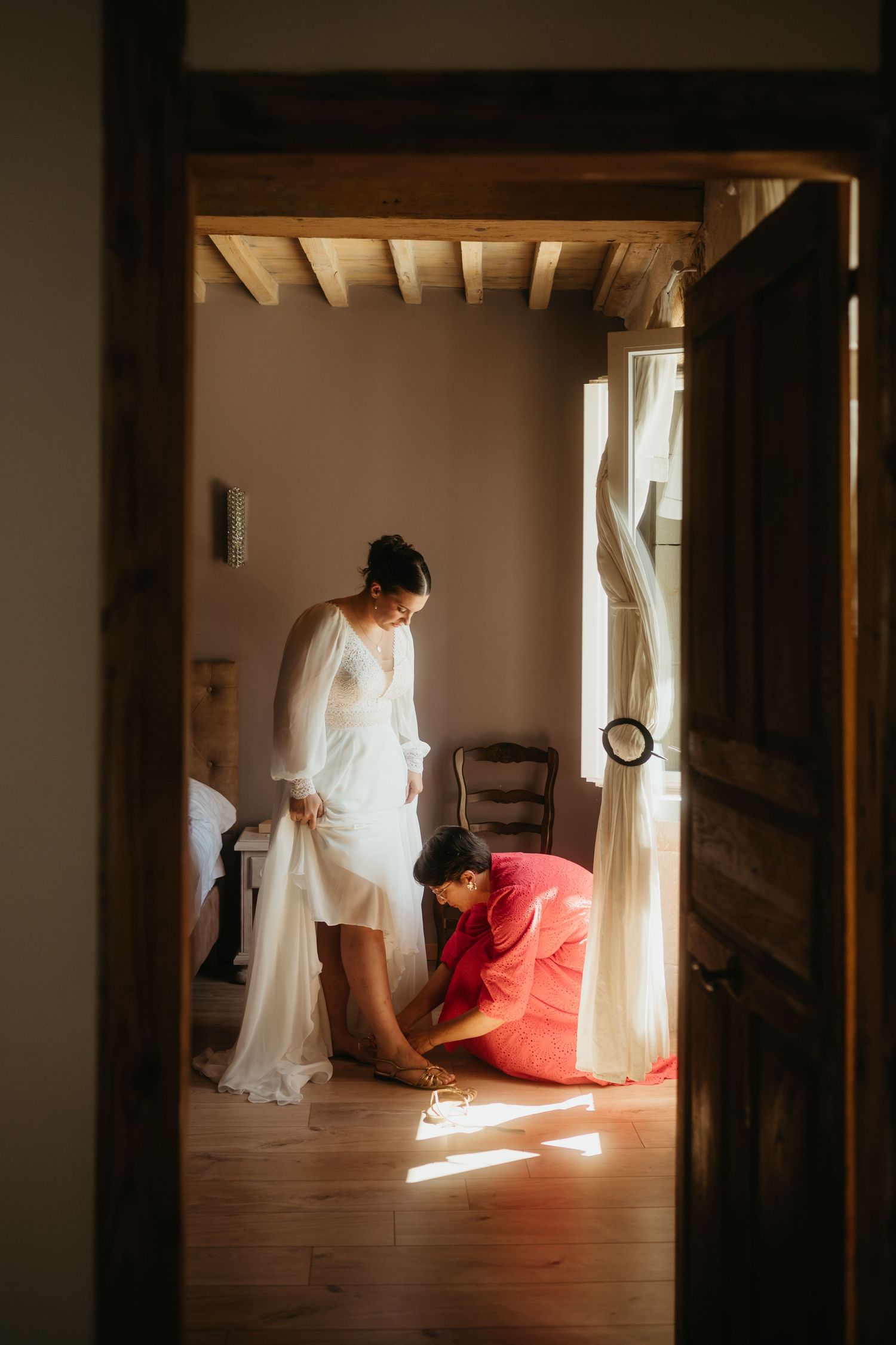 Maman enfilant la chaussure à sa fille en robe de mariée au Domaine les Barraques à Laboulbène, Tarn