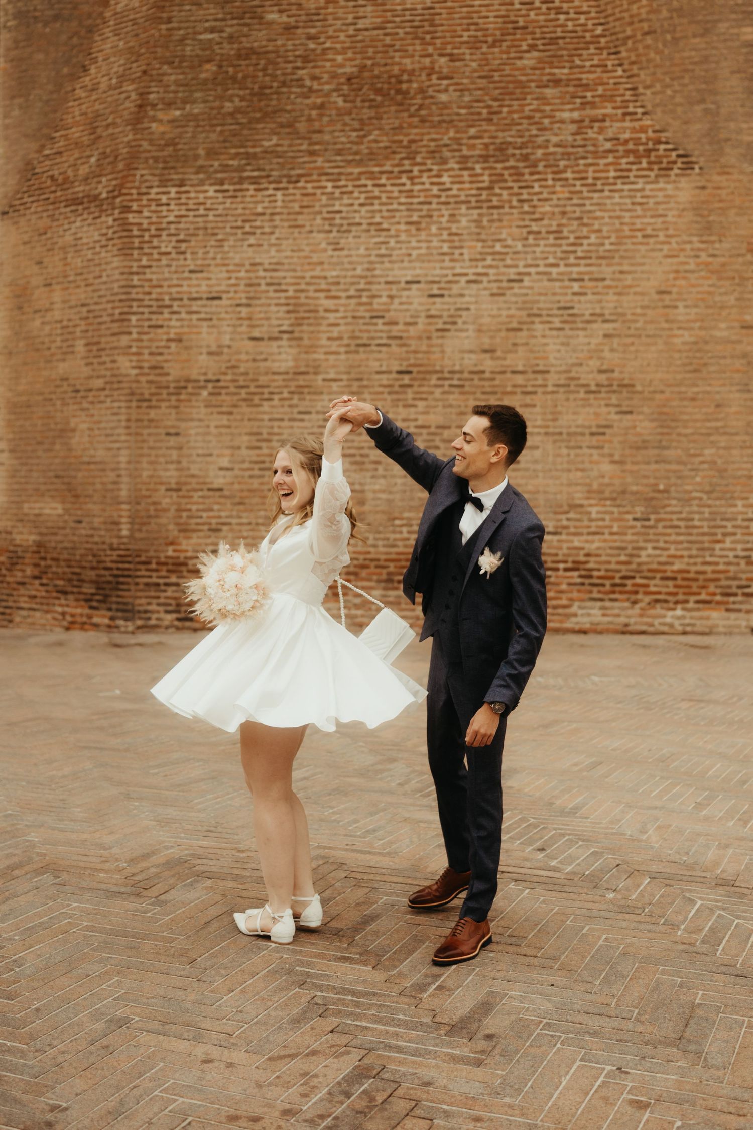 Mariés souriants, le marié faisant tourner la mariée et sa robe courte devant la Cathédrale Sainte Cécile d'Albi