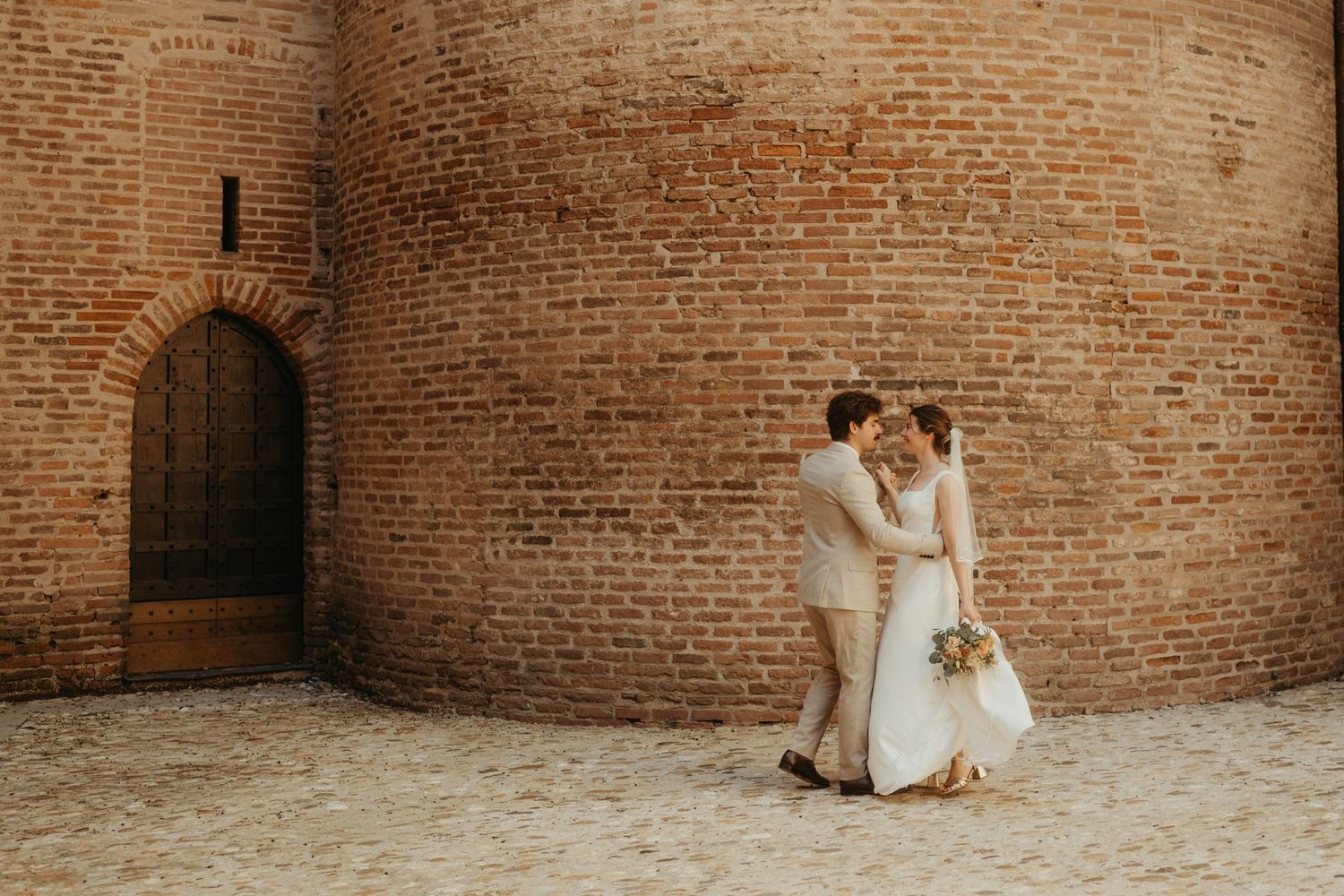 Couple de mariés, dansant devant une tour de briques typiques du Tarn, à Albi