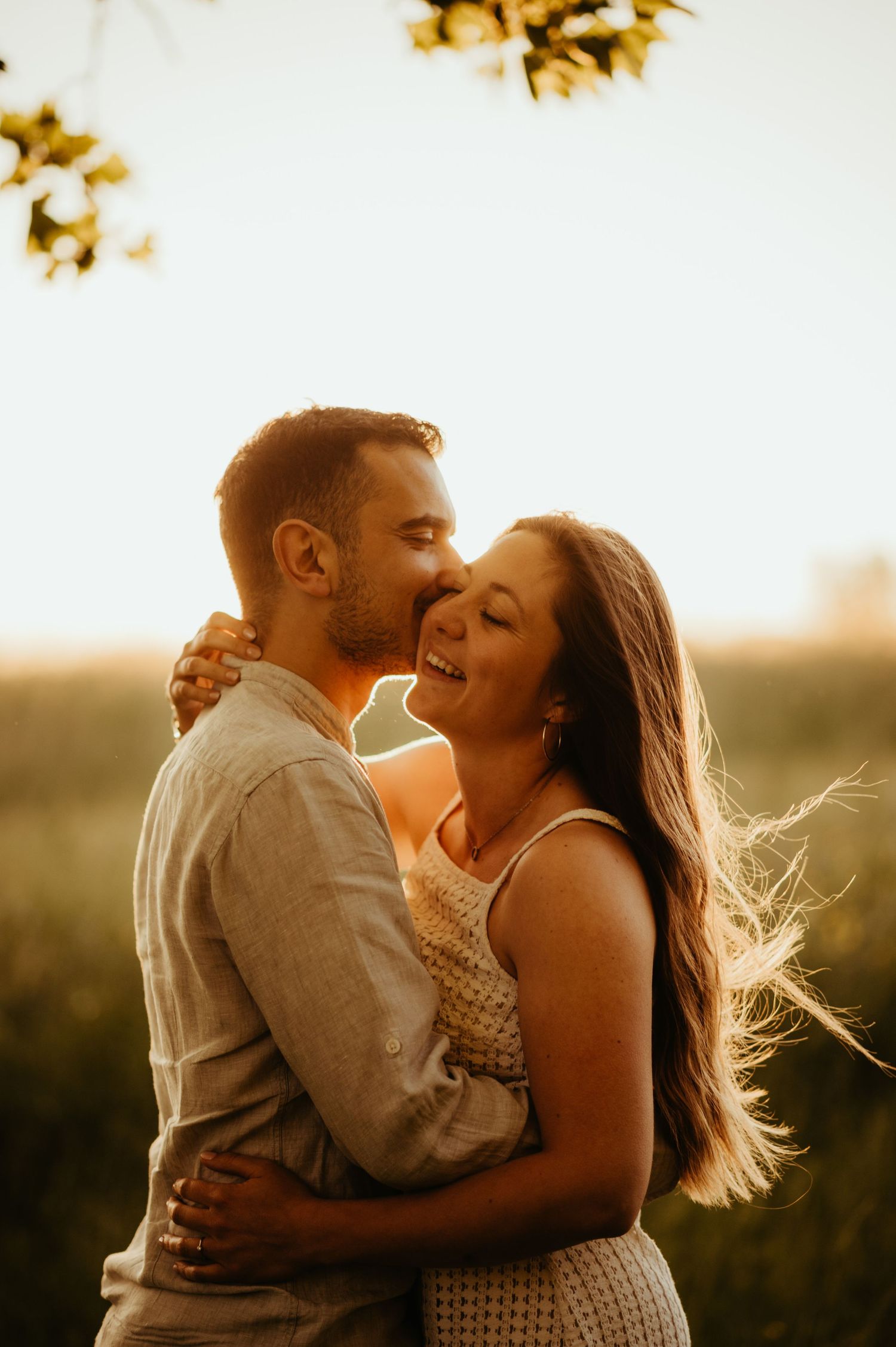 Séance couple heureux, un baiser sur la joue au coucher du soleil à Carmaux