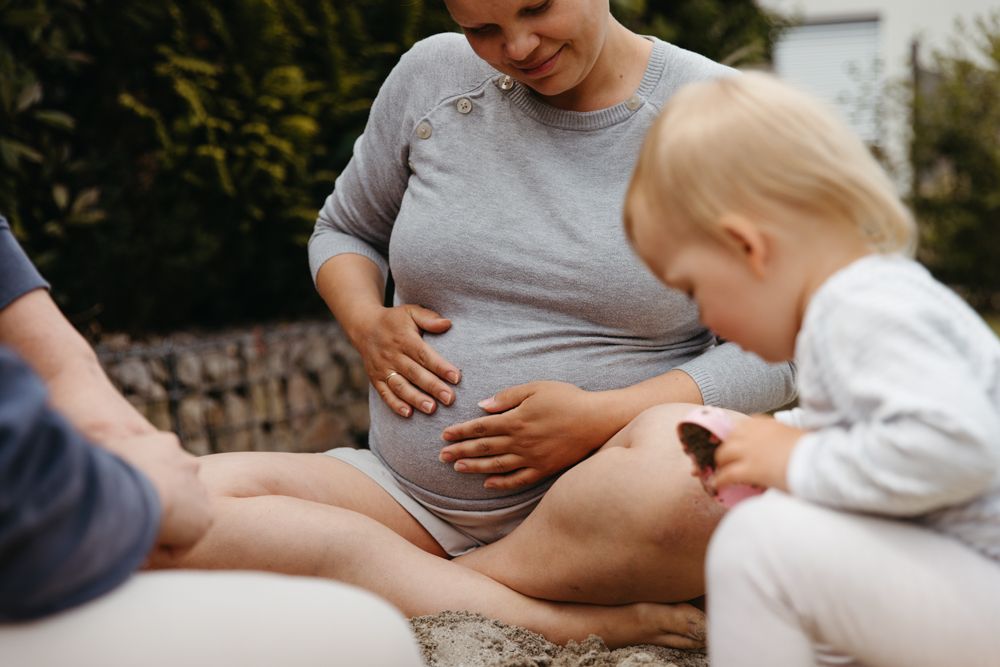 Familienfotografie als Reportage, alltagsnah. Schwangere Mama mit Kind im Sandkasten