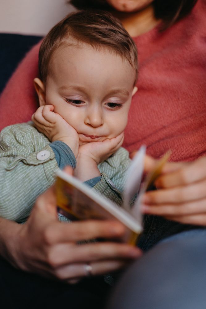 Kind liest konzentriert mit seiner Mama ein Buch, während die beiden von Maria Panzer bei einem Familienfotoshooting fotografiert werden