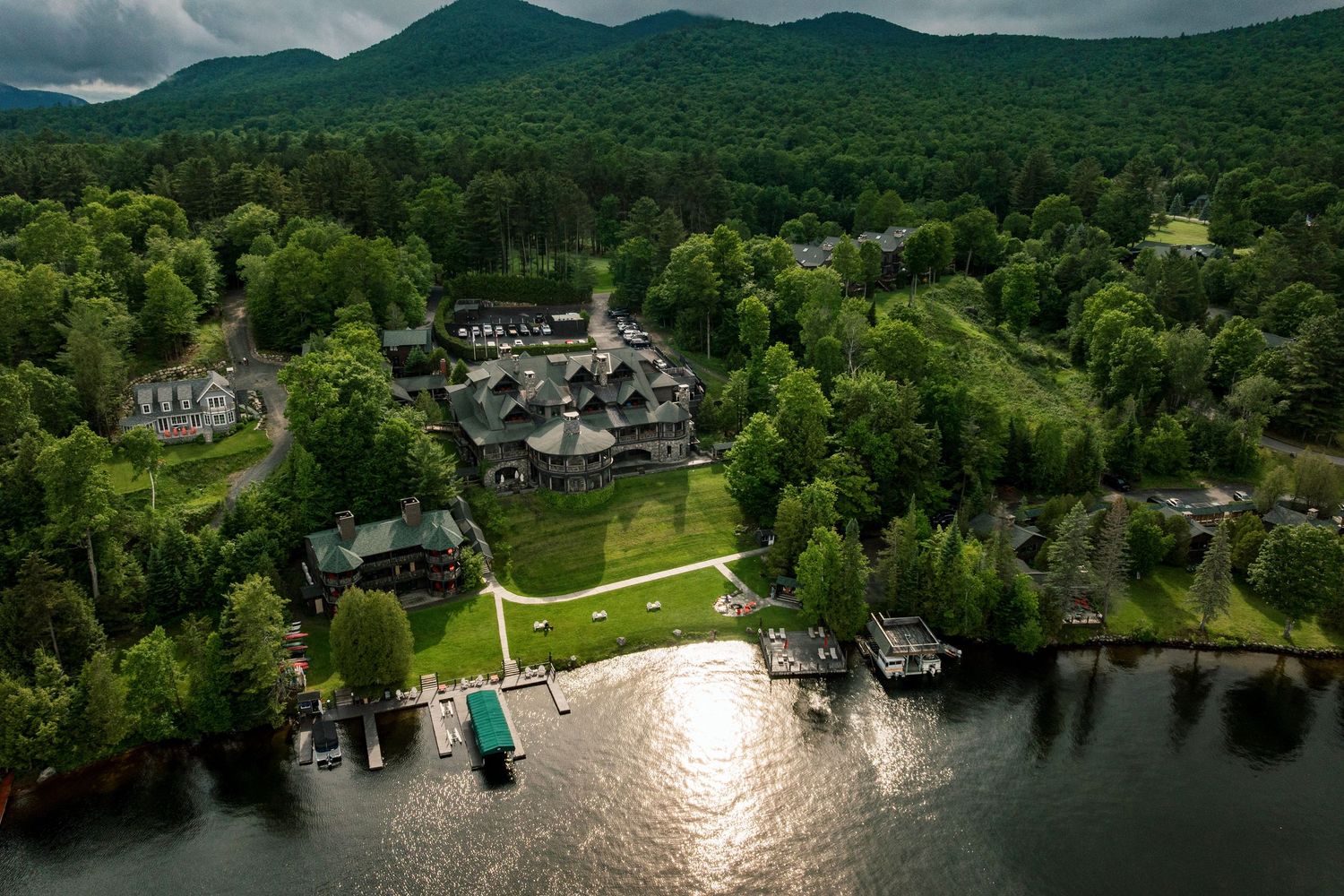Aerial view of Lake Placid Lodge surrounded by dense forest and mountain scenery along a serene lakefront.
