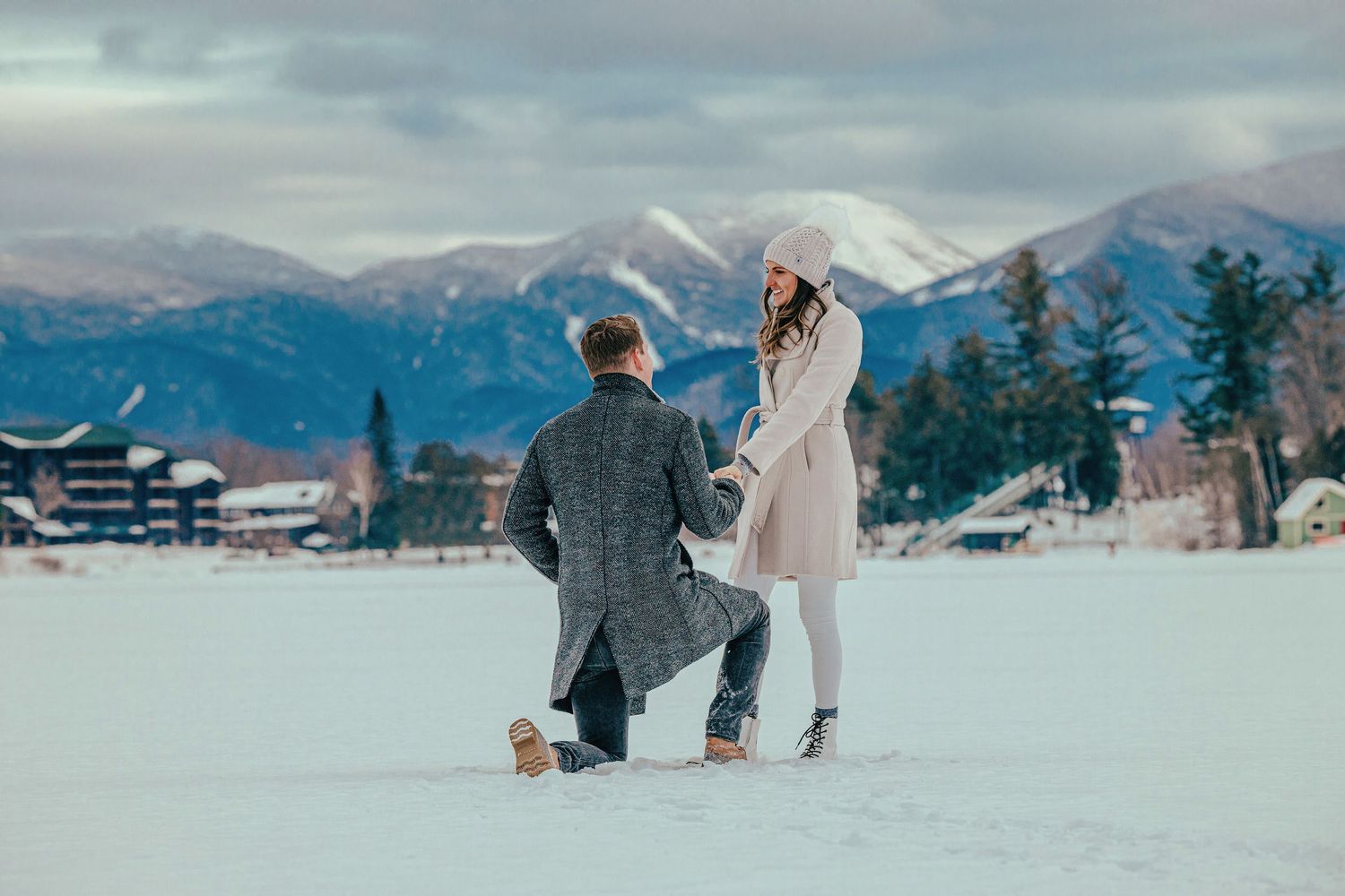 A romantic winter proposal moment against a backdrop of snow-capped mountains.
