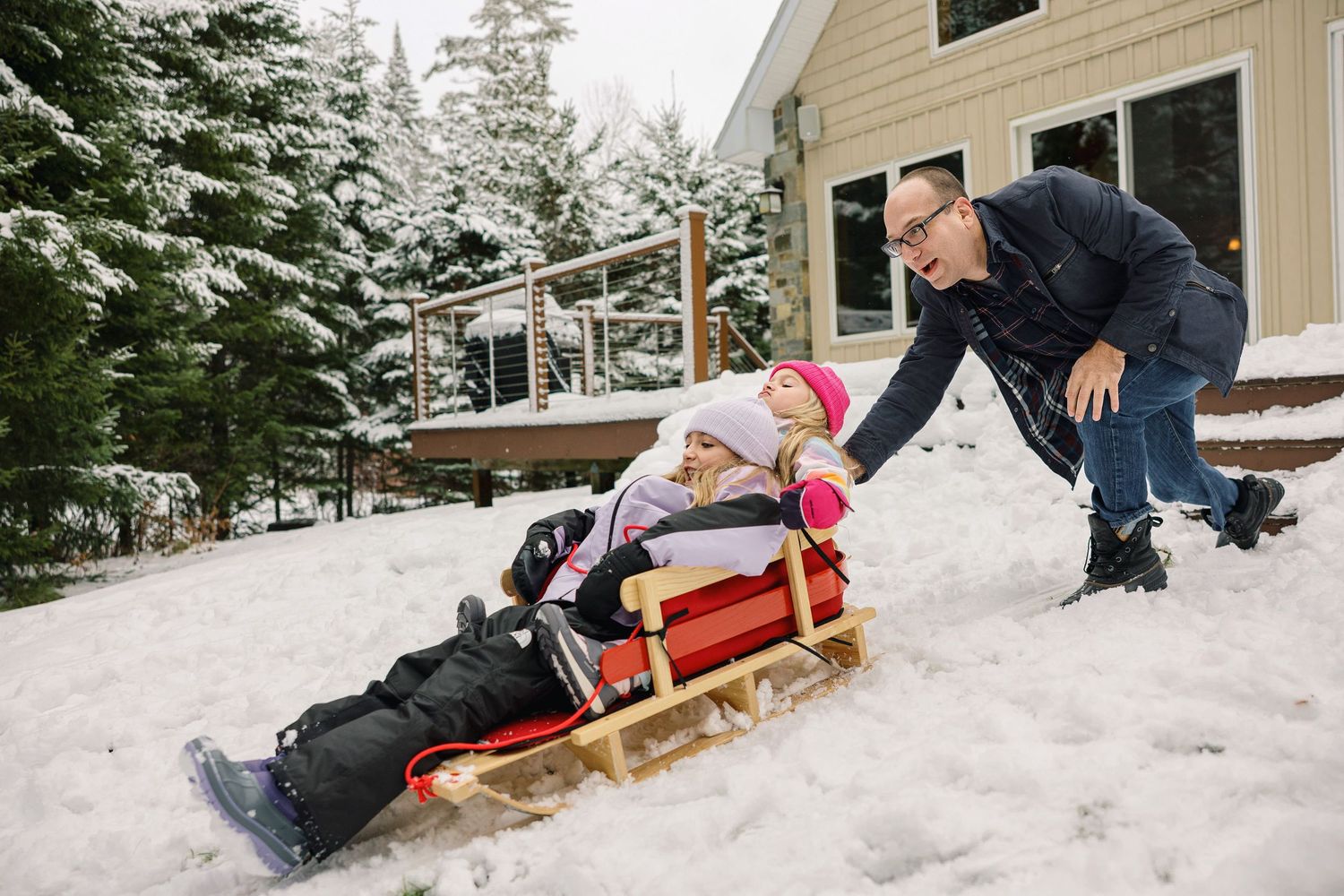 A sequence of action shots showing someone sledding down a snowy hill on a wooden toboggan in winter.