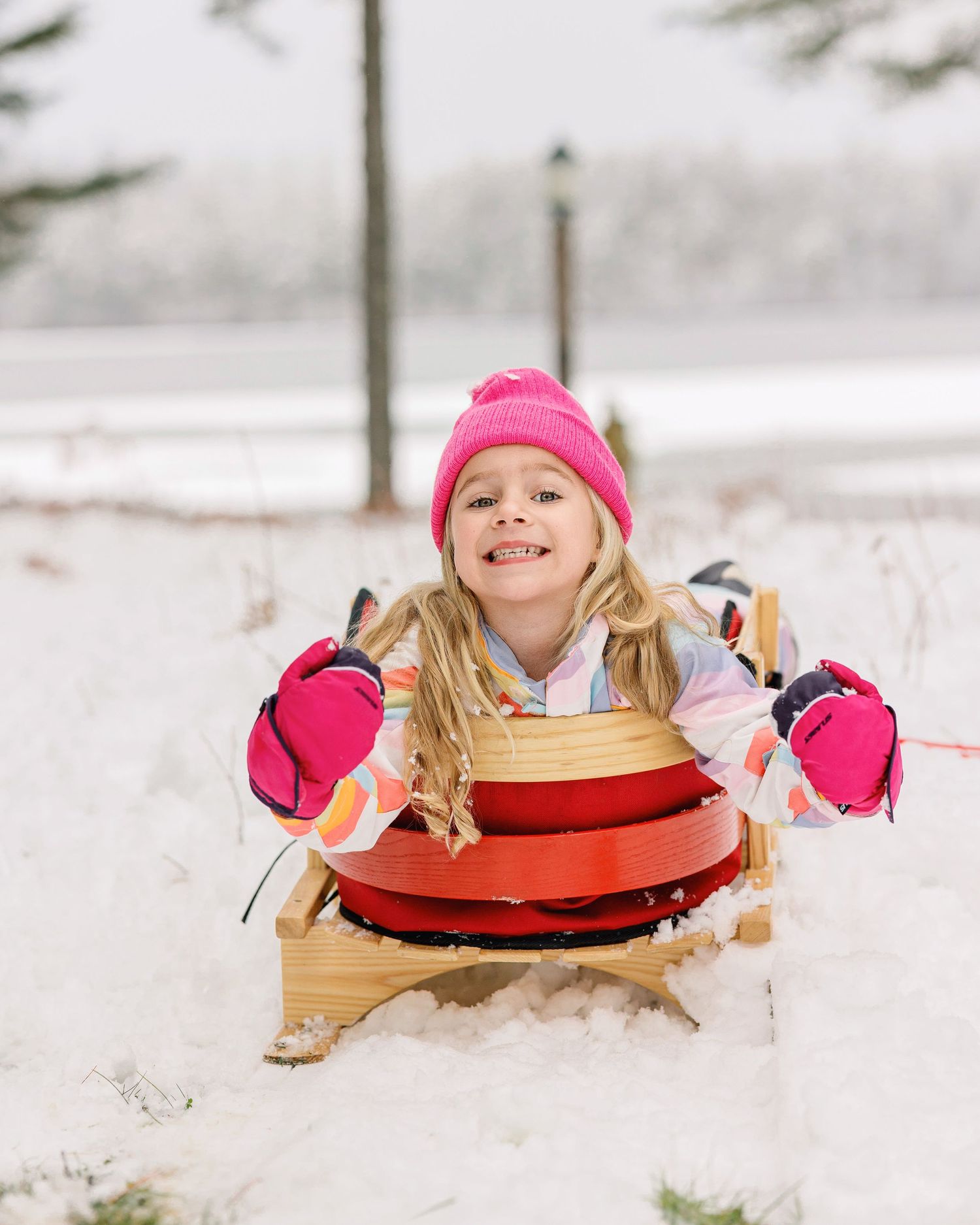 Child having fun sledding on a red disc sled in fresh winter snow.