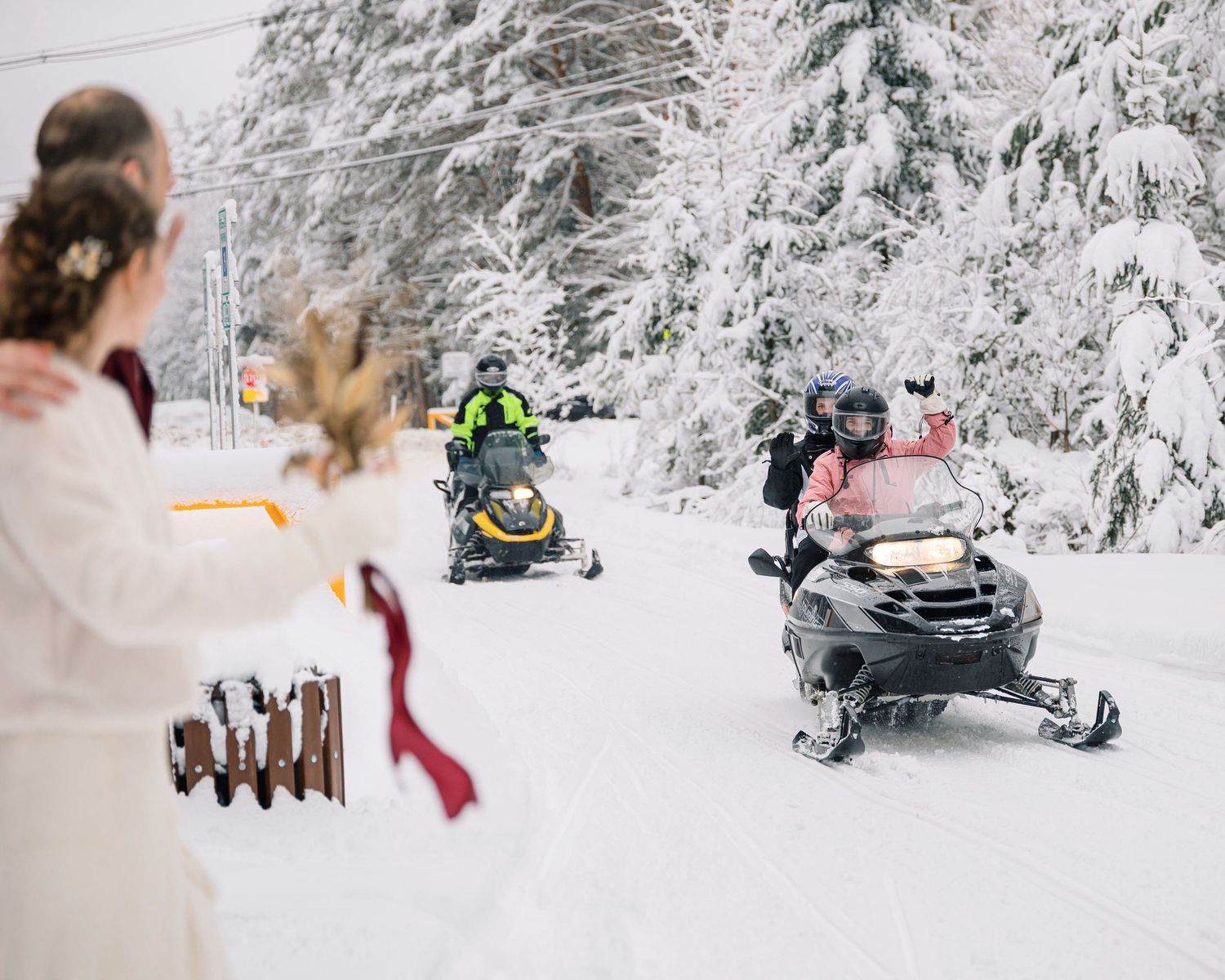 A winter wonderland scene with snow-covered trees and snowmobiles parked in a pristine white landscape.