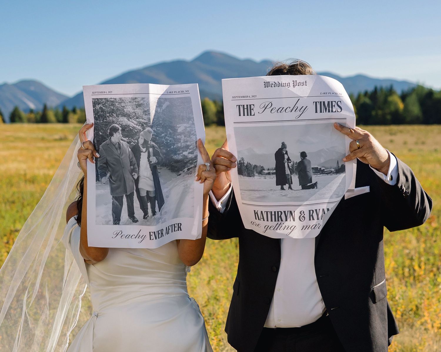 Newlyweds hold custom wedding newspapers outdoors with mountain backdrop on their wedding day.